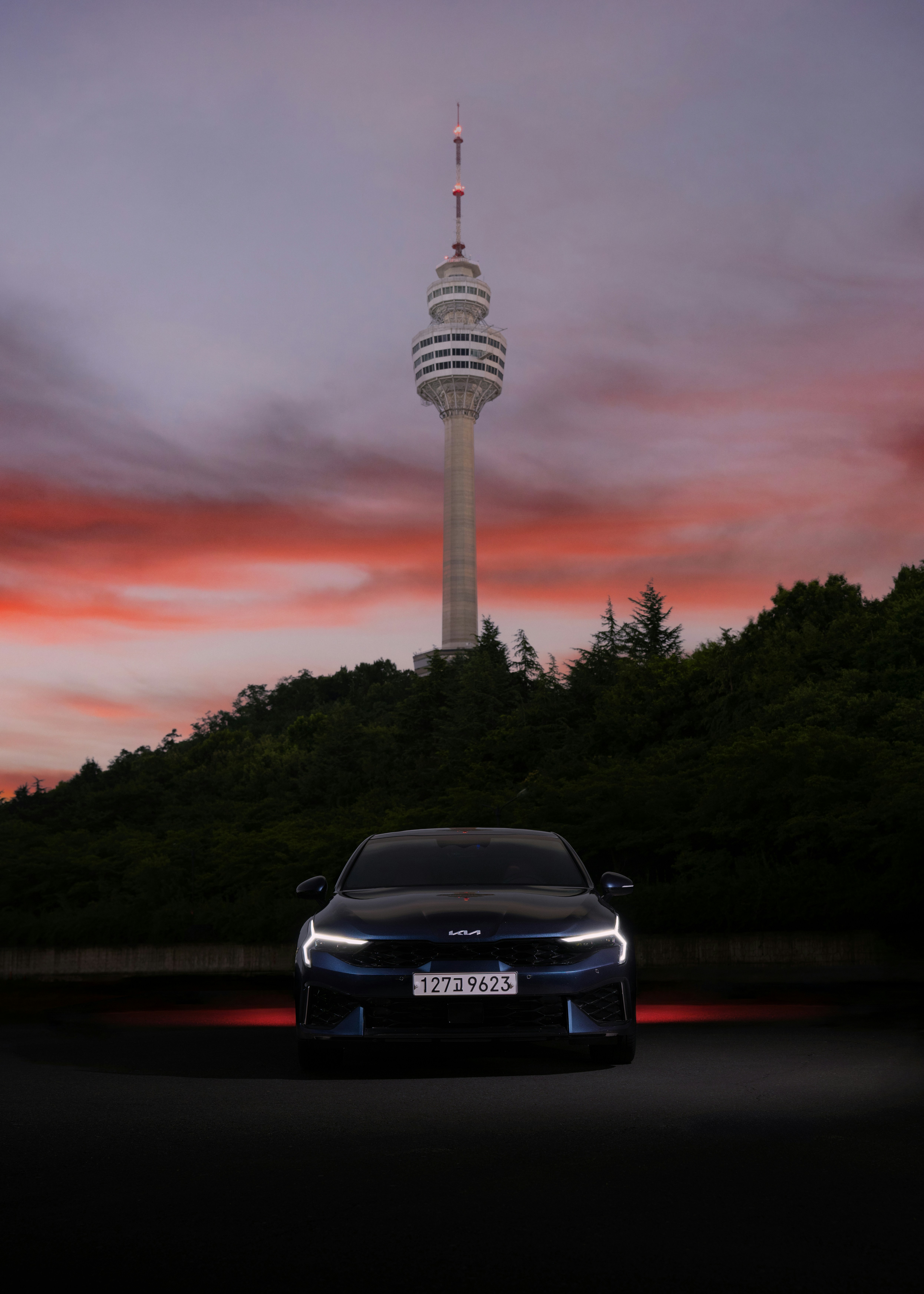 Car parked in front of a tower at sunset