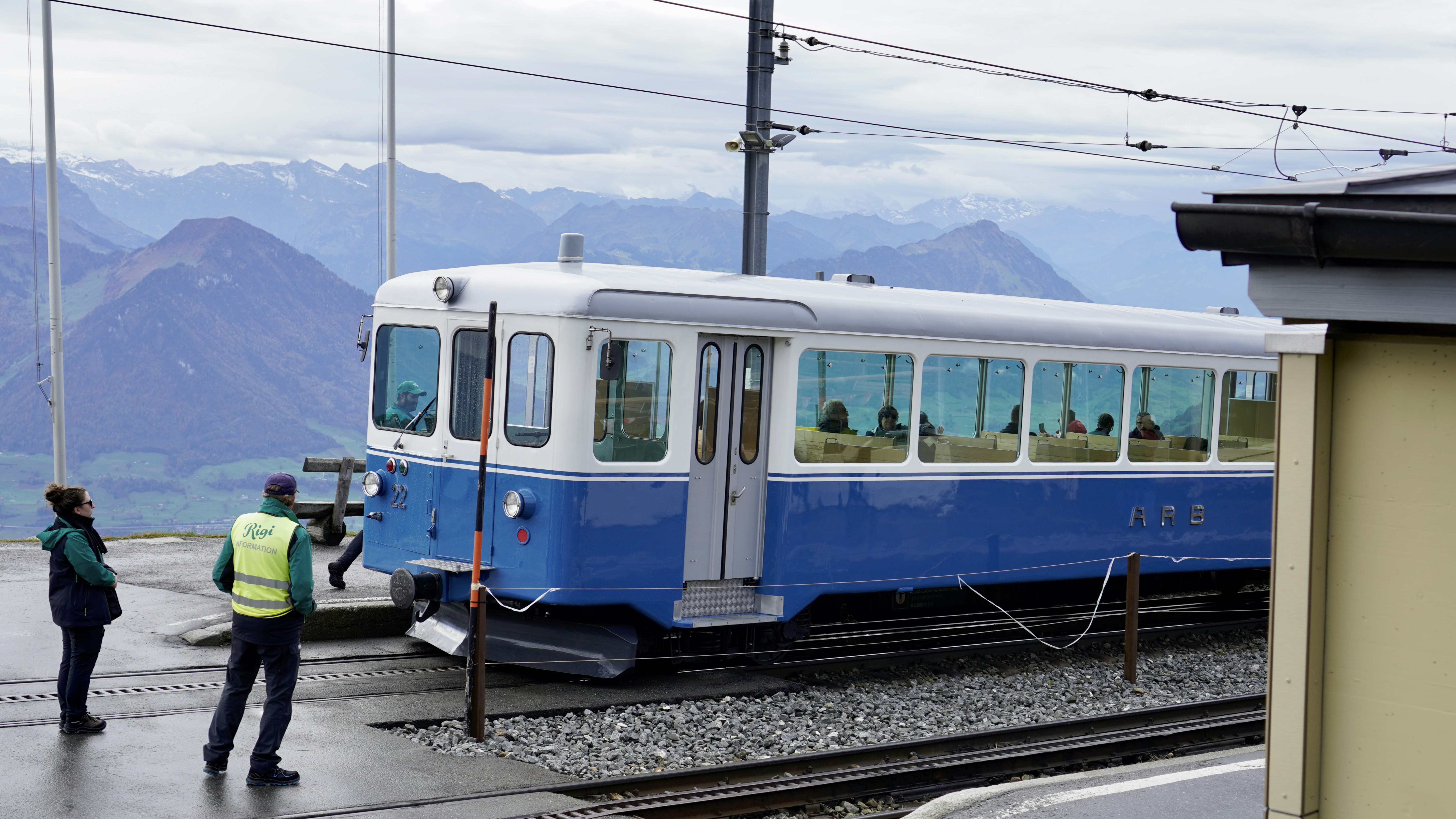 Blue and white train on tracks with mountains behind
