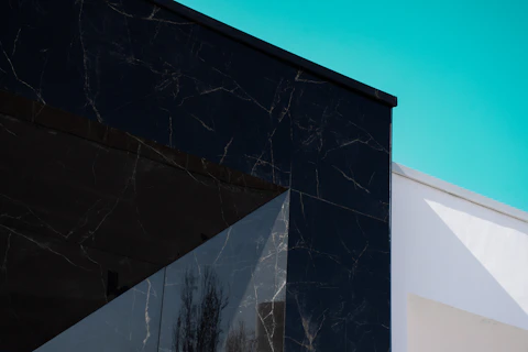 Black marble building corner against bright blue sky