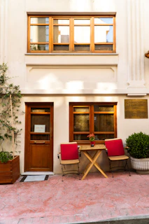 Two chairs and table outside a building entrance.