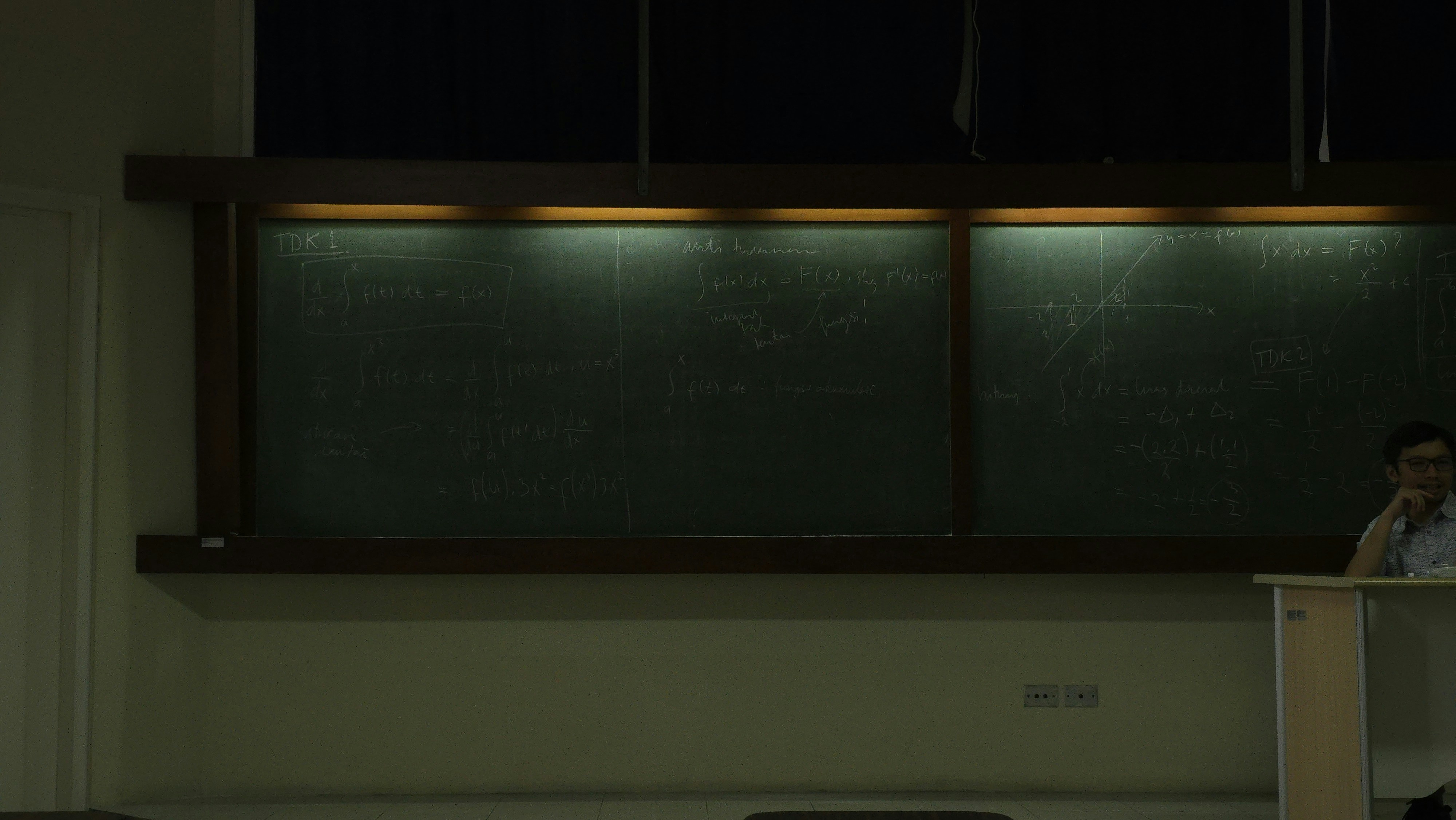 Man standing near a chalkboard in a classroom