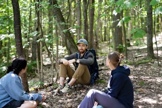 Three people resting in a sunlit forest