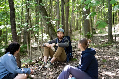 Three people resting in a sunlit forest