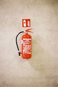 Red fire extinguisher mounted on a concrete wall.