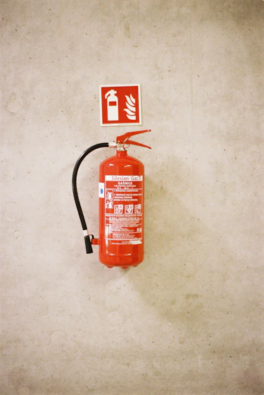 Red fire extinguisher mounted on a concrete wall.