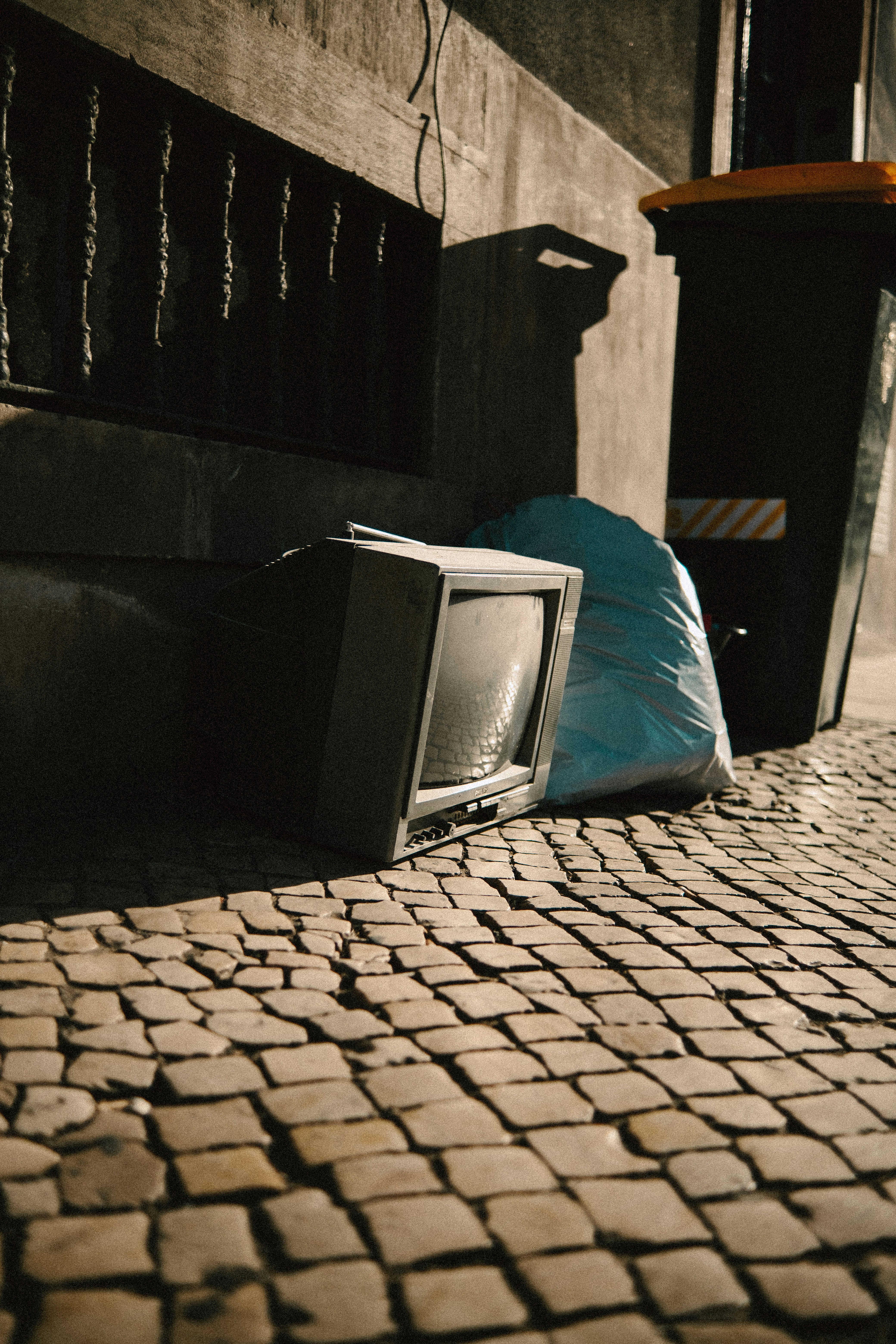 Alter Fernseher und Müllsäcke auf der Kopfsteinpflasterstraße.