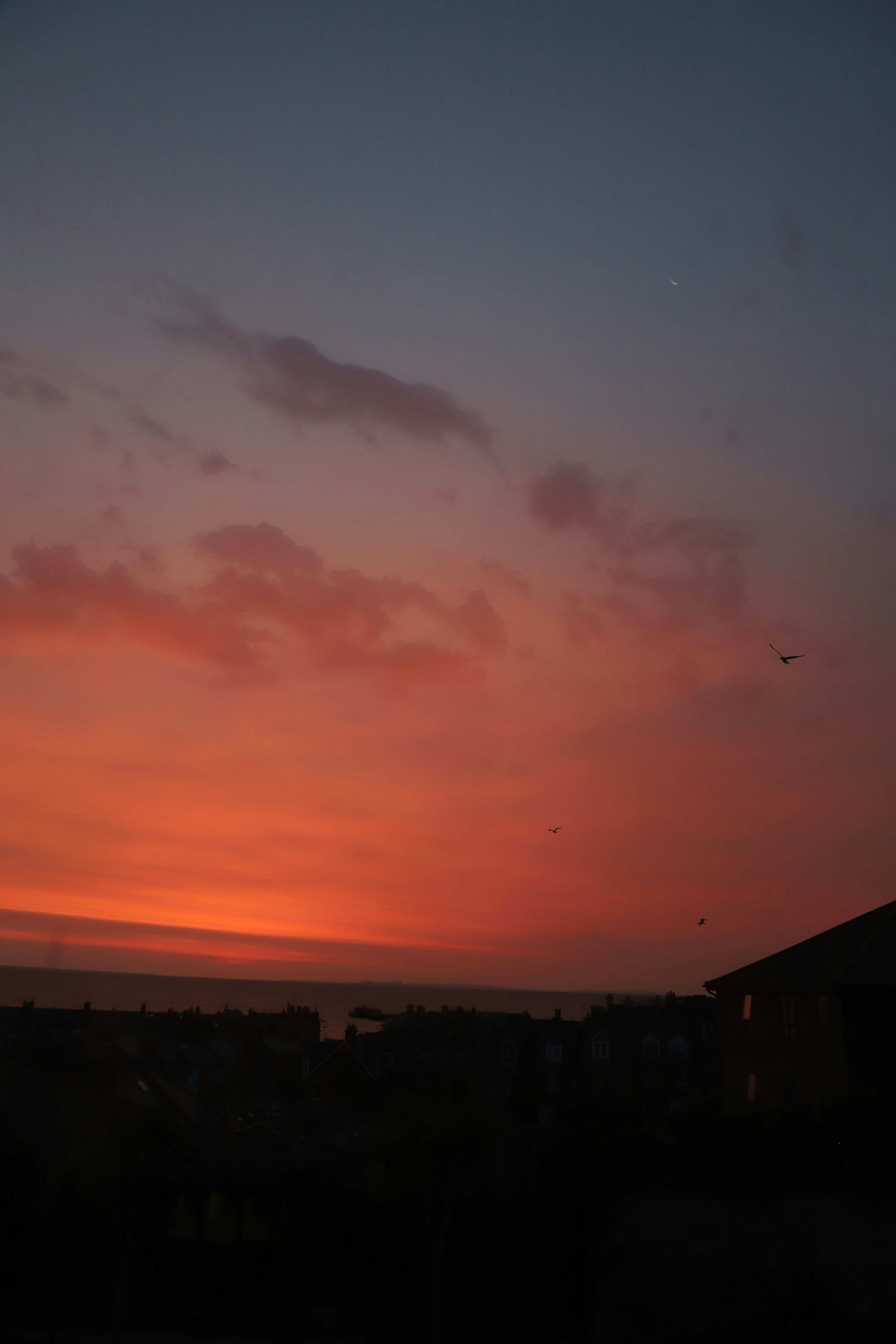 Vibrant sunset sky over a dark landscape.