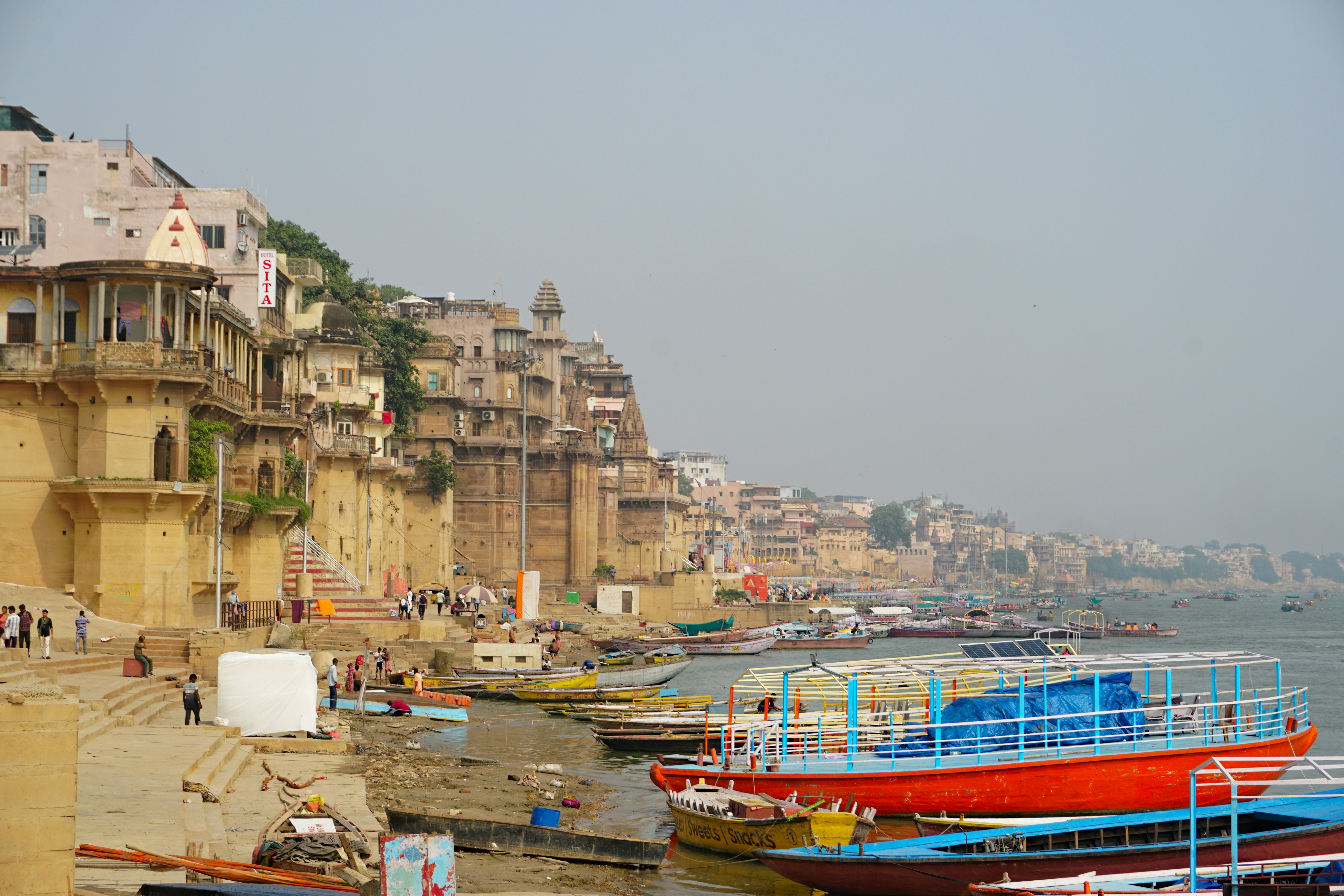 Boats moored along the ganges river with city buildings.