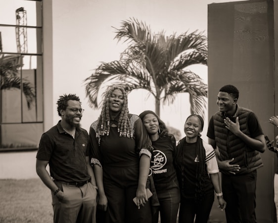 Group of five people smiling outdoors with palm tree