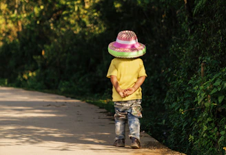 Child wearing a large hat stands outdoors