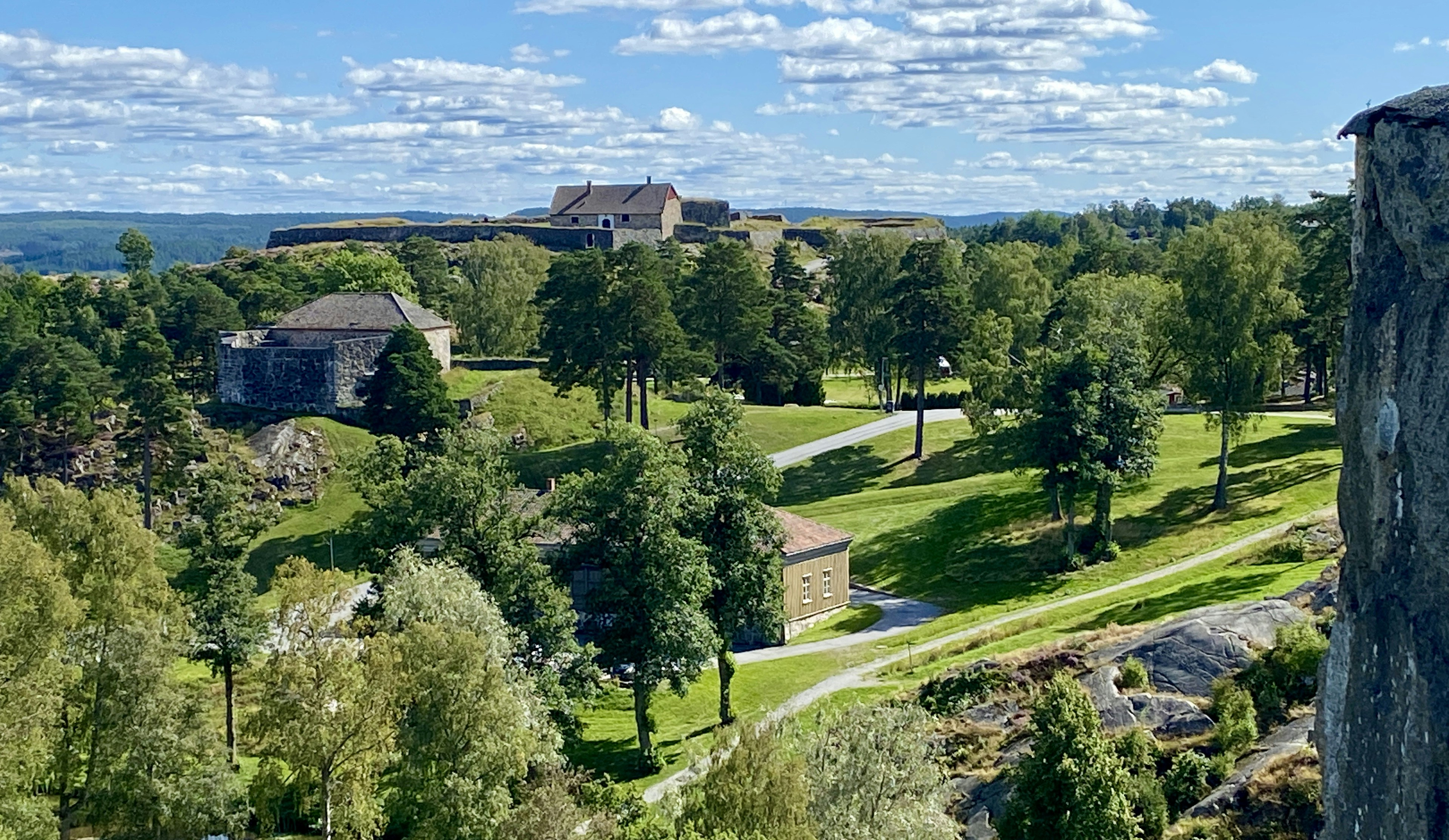 Historic fortress buildings surrounded by green trees and grass