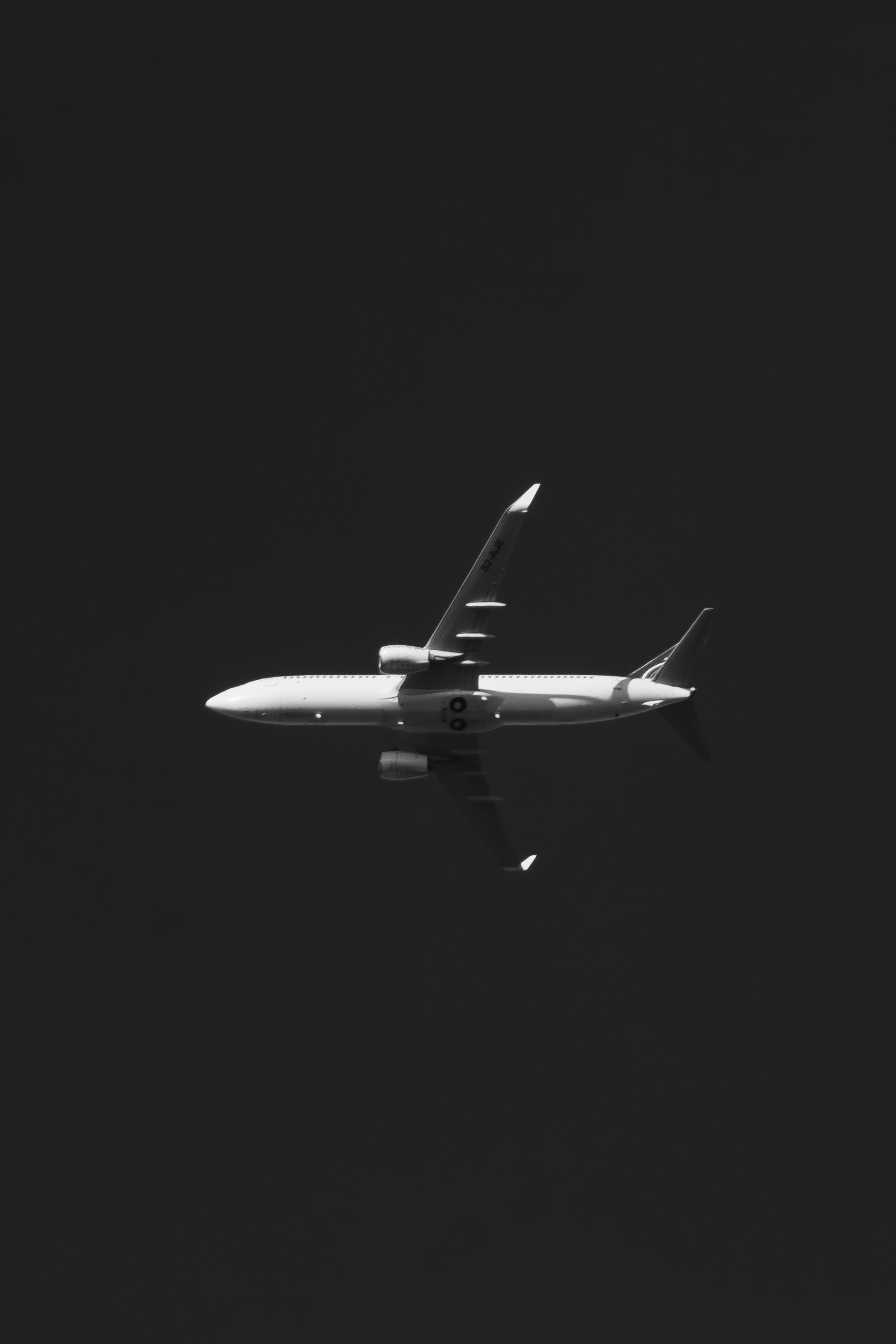 Um avião branco voando contra um fundo escuro