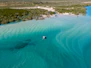 Small boat floats on turquoise water with sandbars.