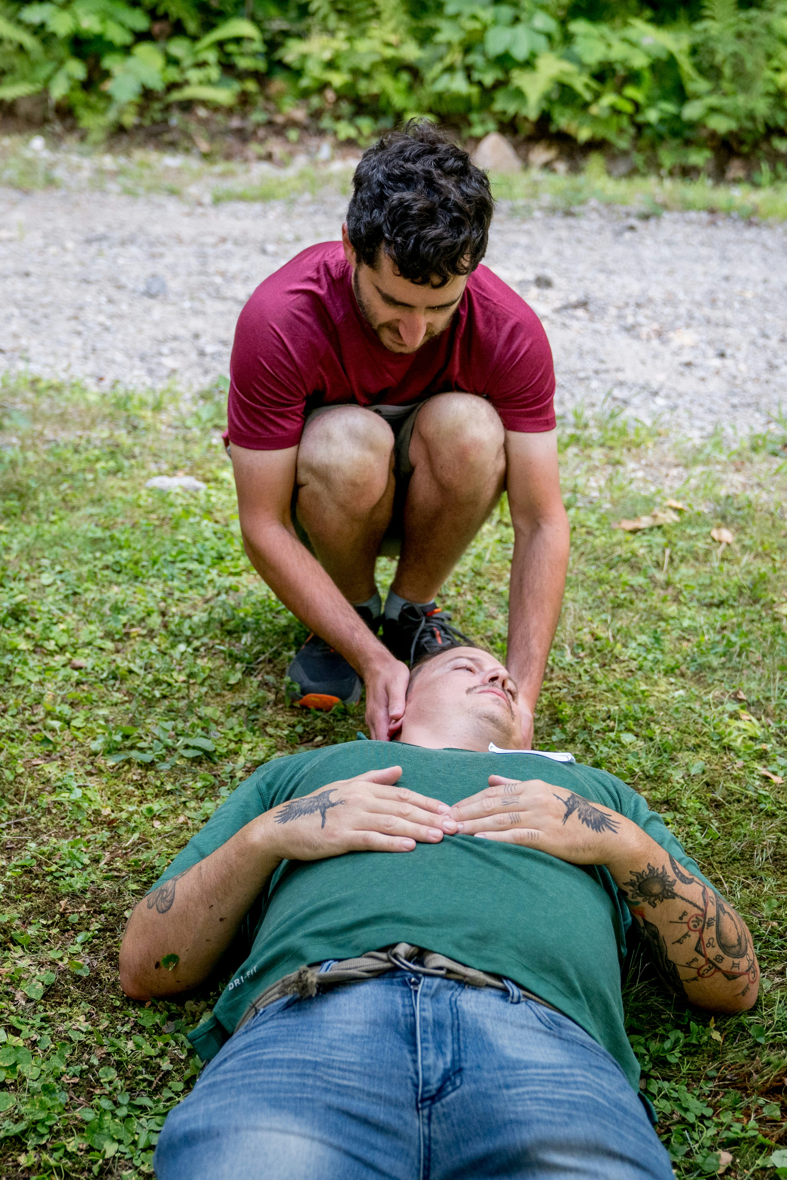 Man performs cpr on another man lying down