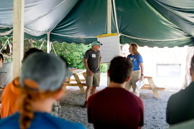 People gathered under a tent for a presentation