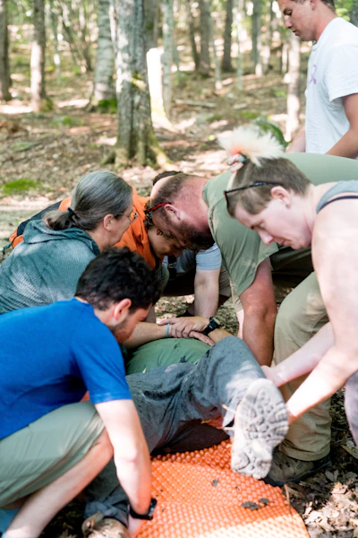 People helping an injured person in a forest.