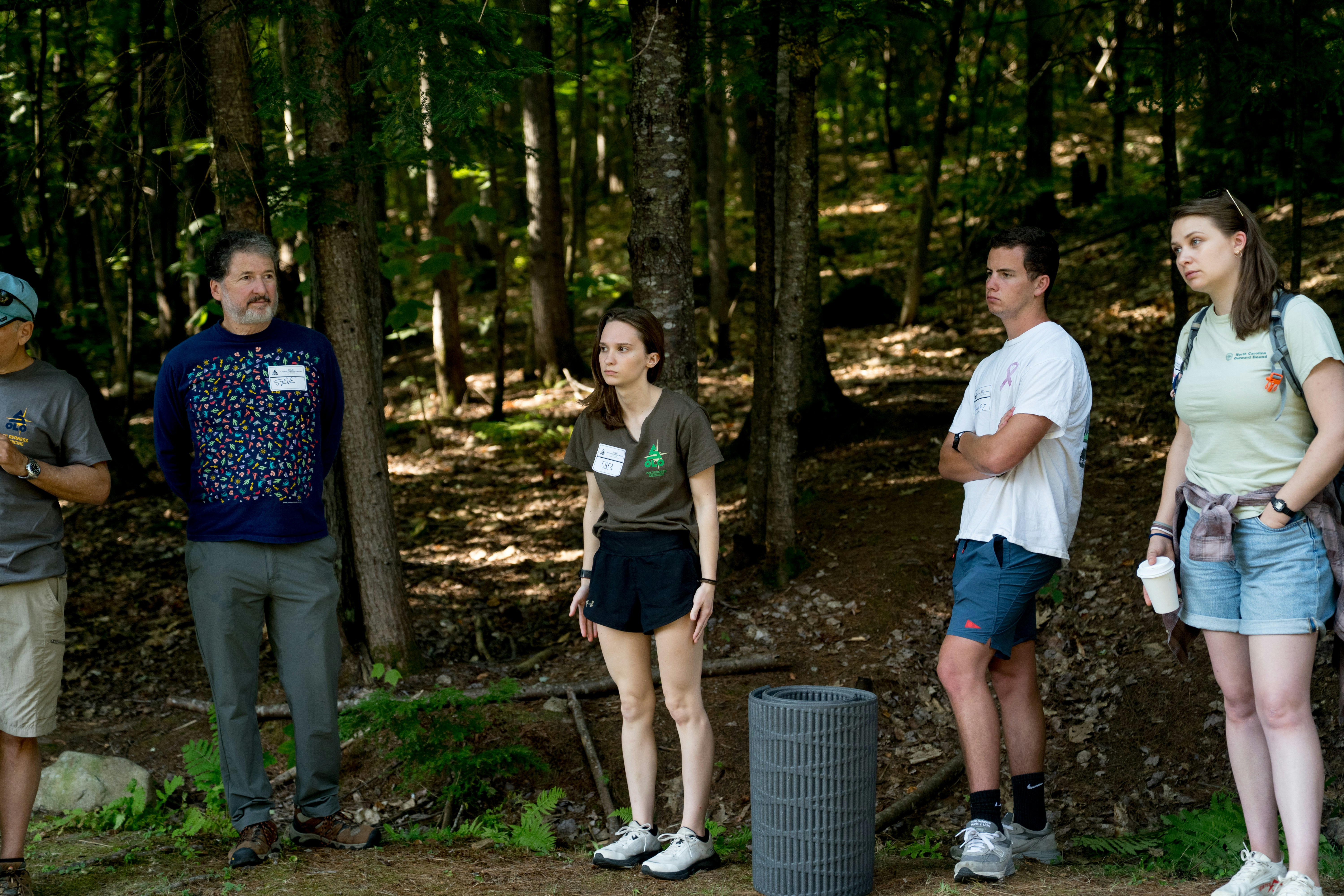 Žmonės einantys miško taku rytinėje šviesoje