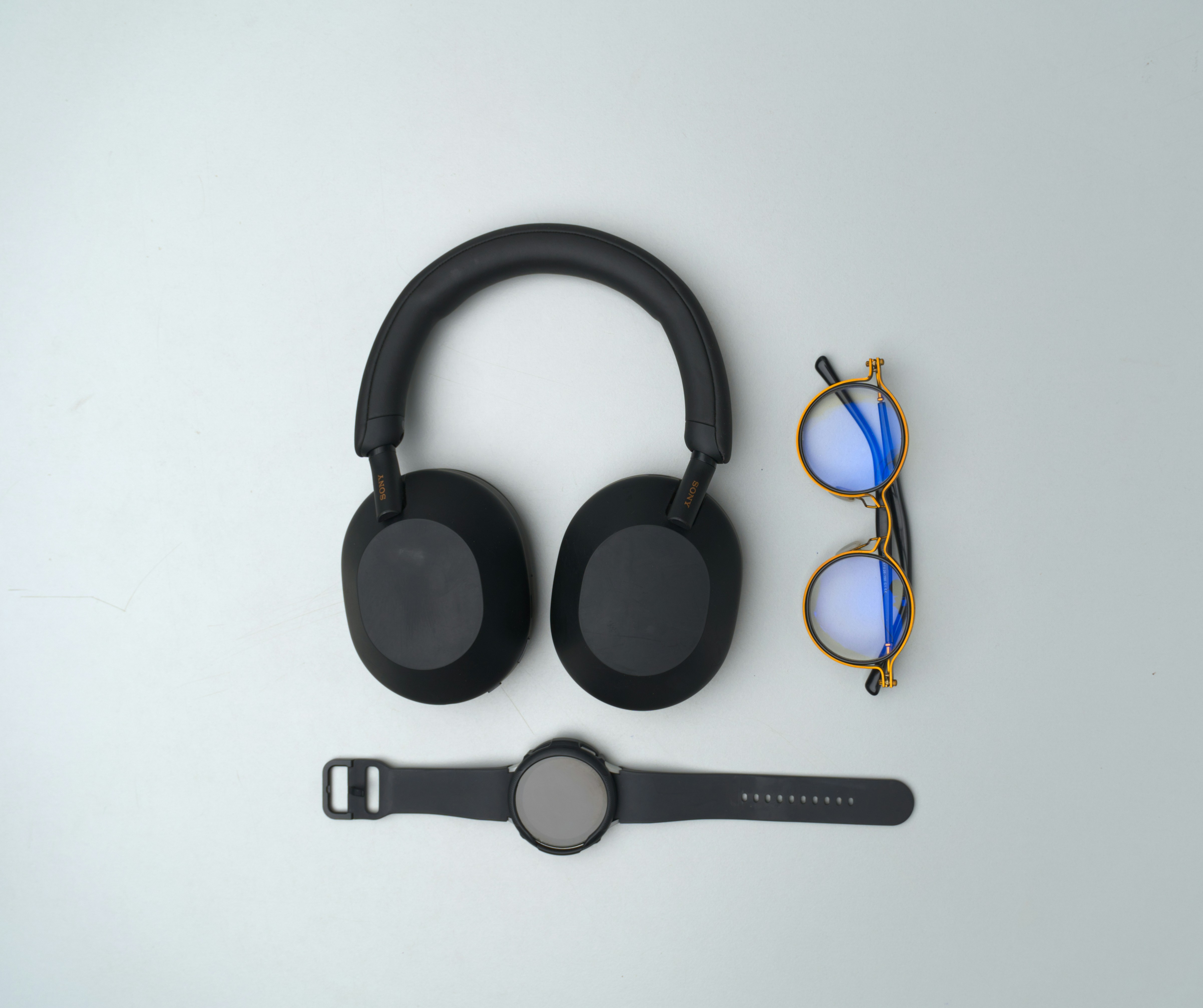 Black headphones, glasses, and smartwatch on gray background.