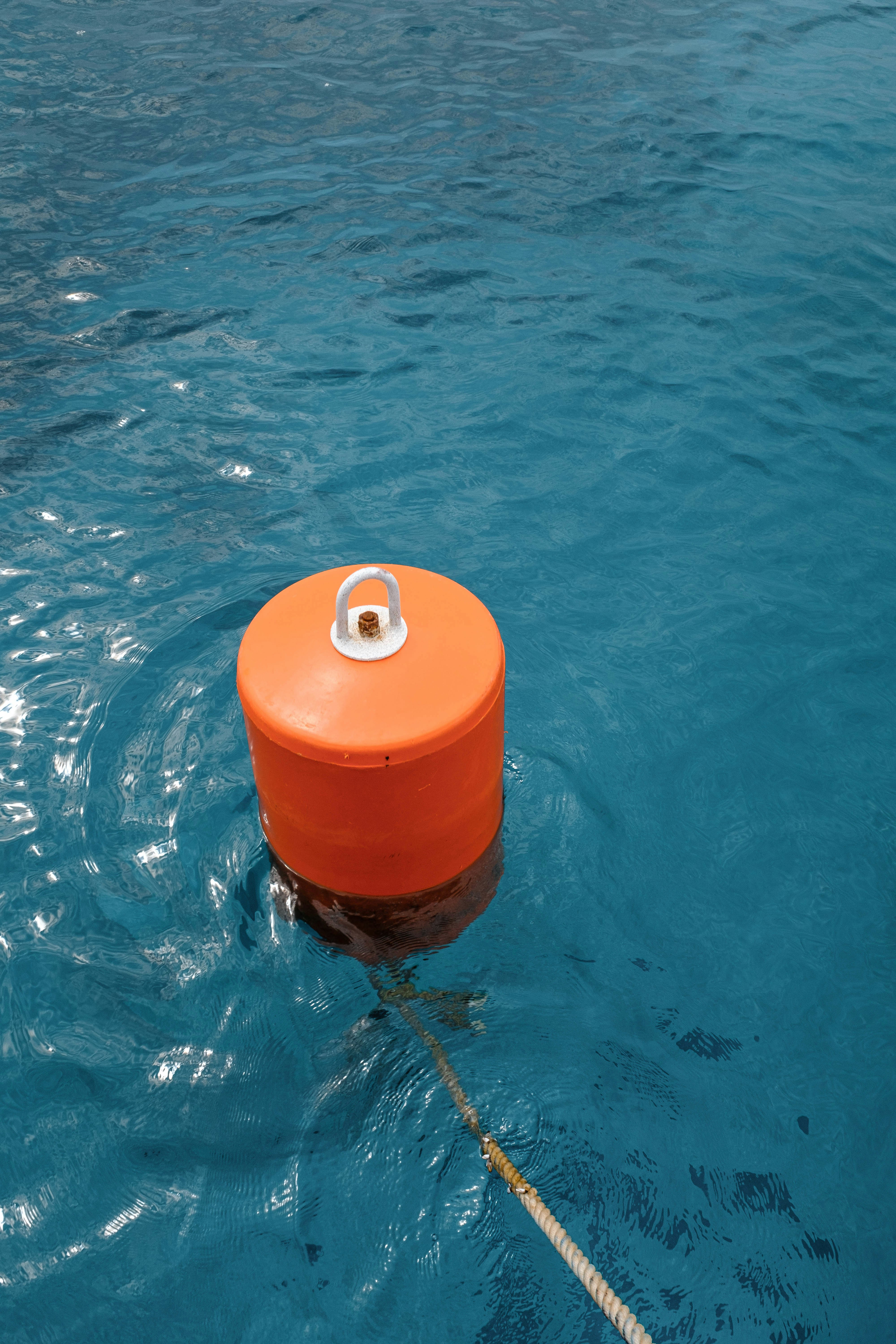 Orange buoy floating on clear blue water