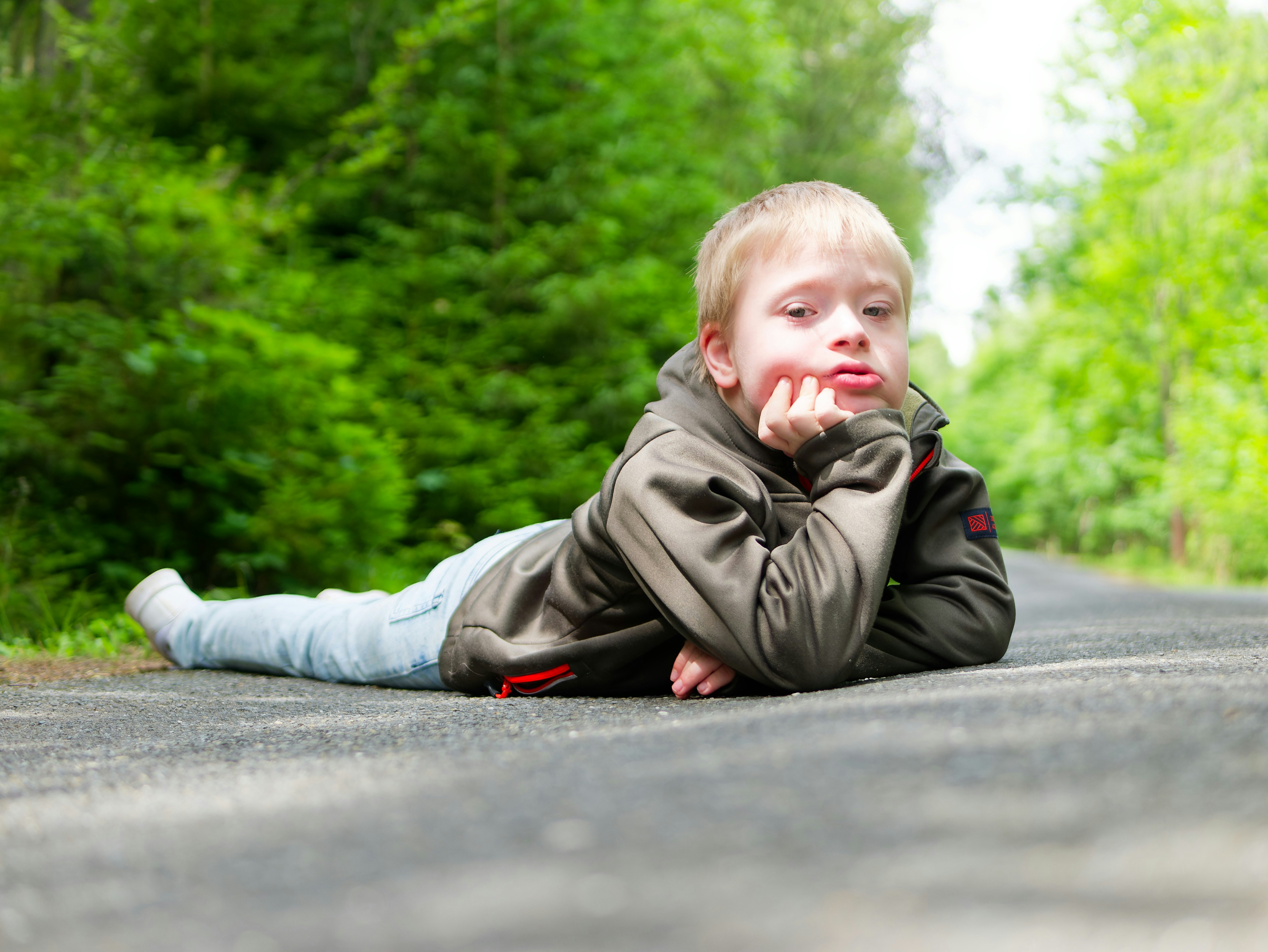 Young boy lying on a path in the woods