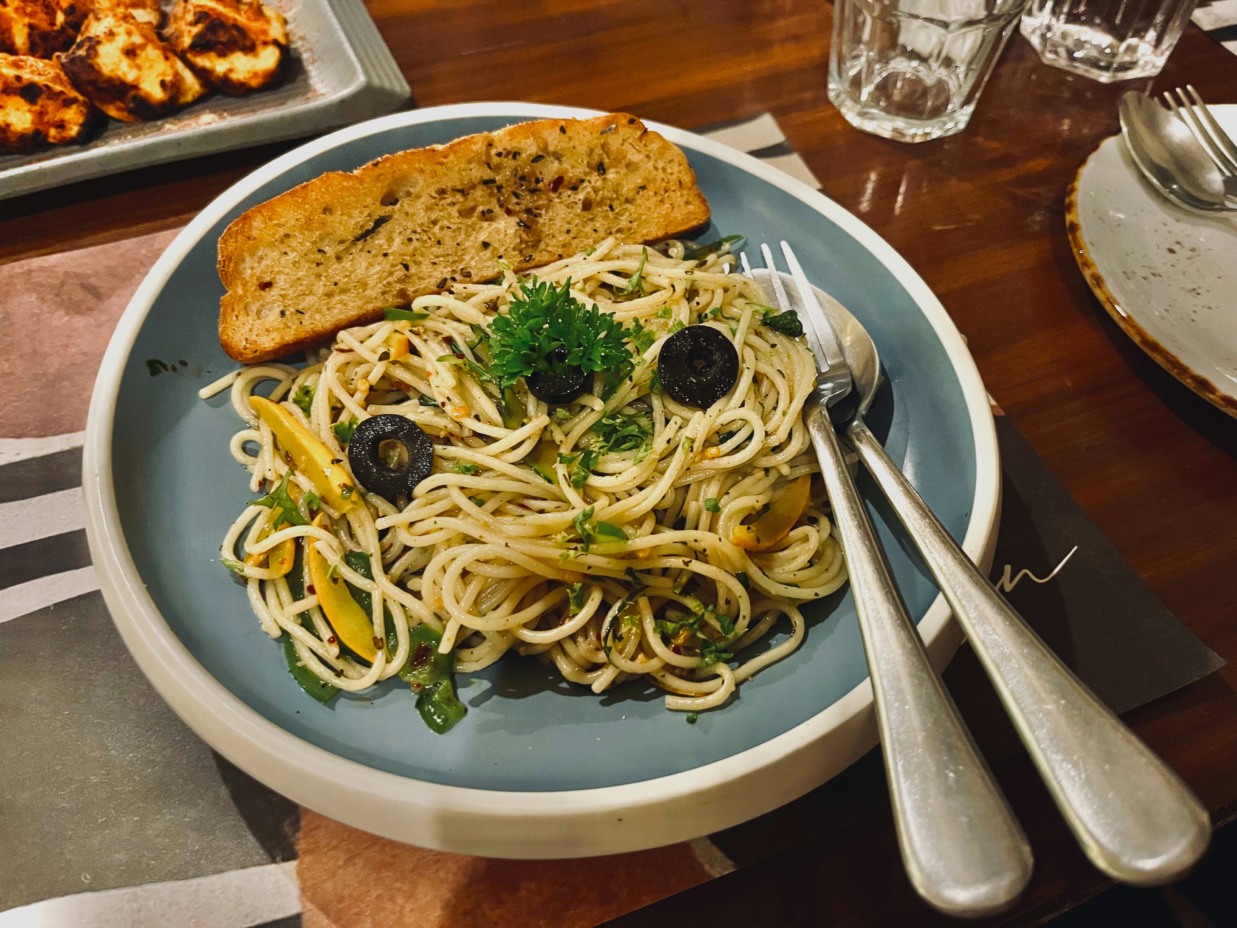 Spaghetti with olives and garlic bread on a plate