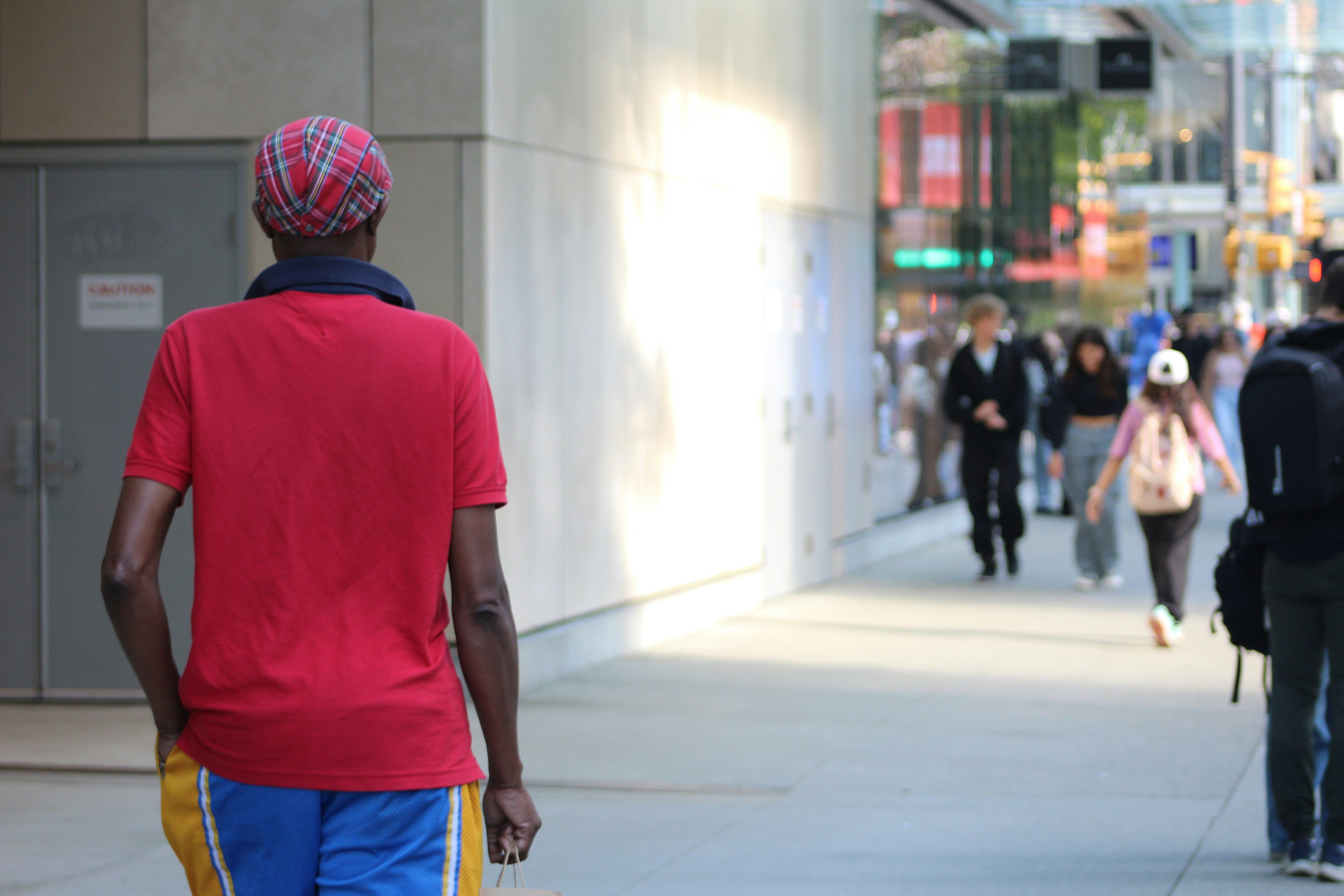L'uomo in camicia rossa cammina lungo il marciapiede della città