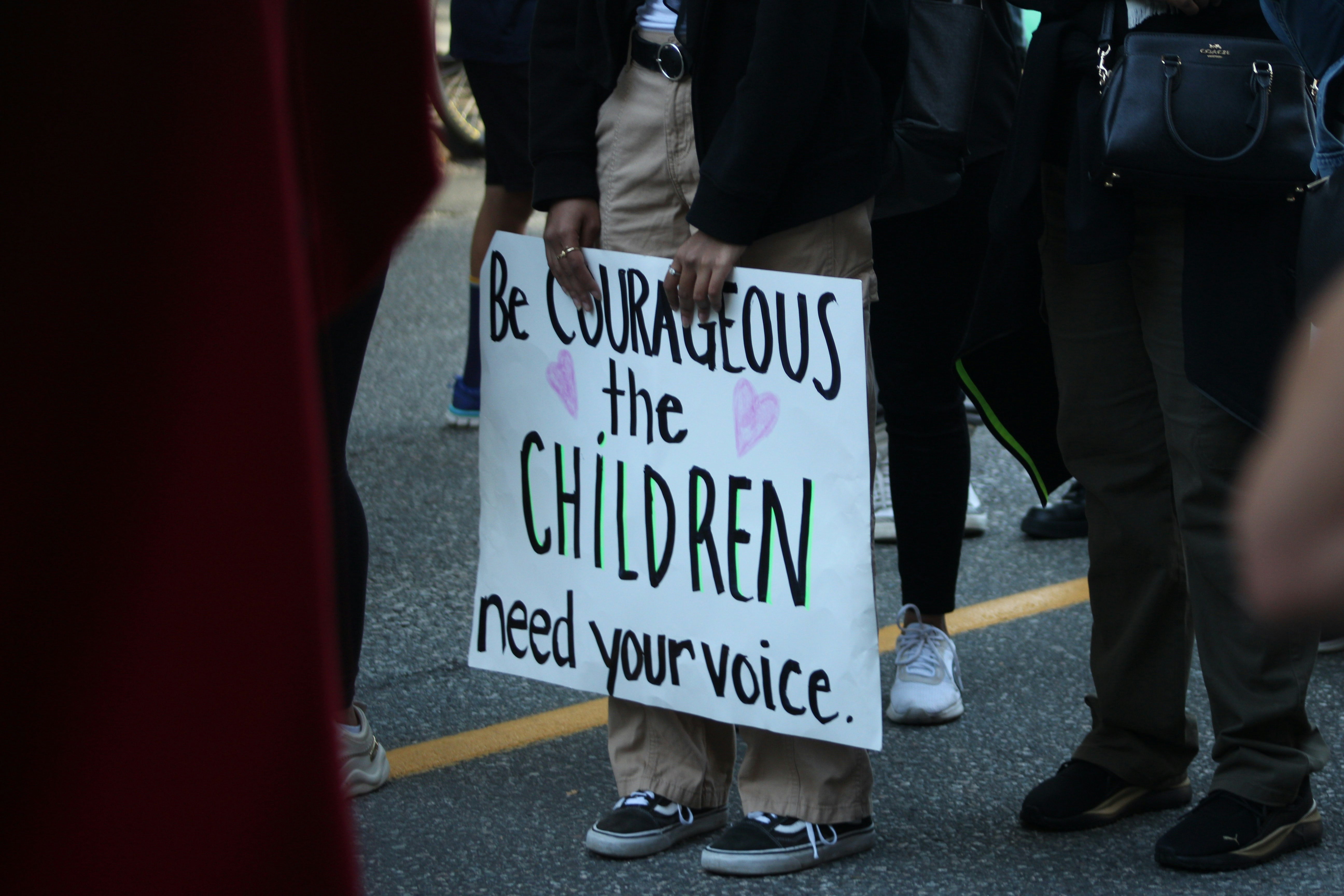 Person holding sign about children needing voice.