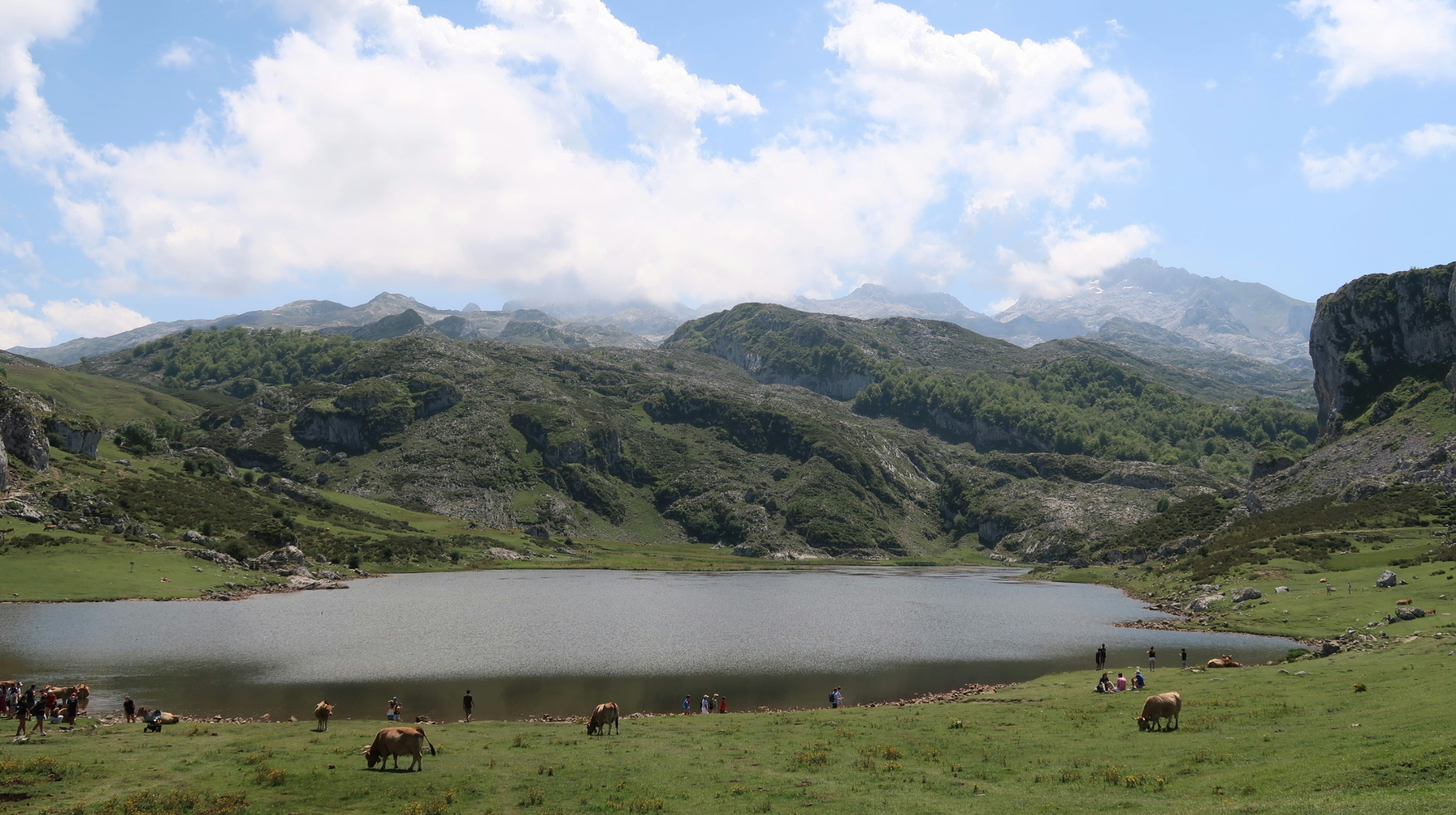 A serene lake surrounded by green hills and mountains.