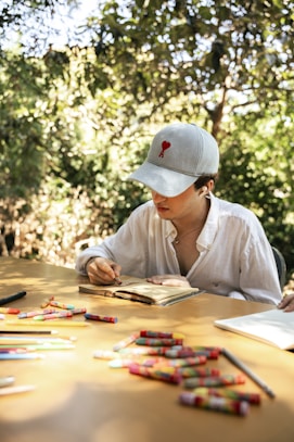 Person drawing in notebook with crayons at table