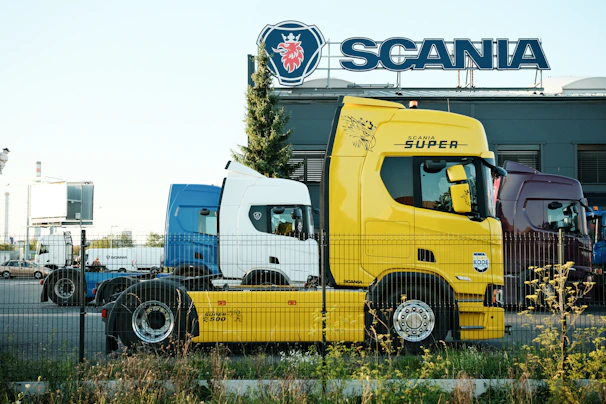 Yellow and blue trucks parked outside scania building