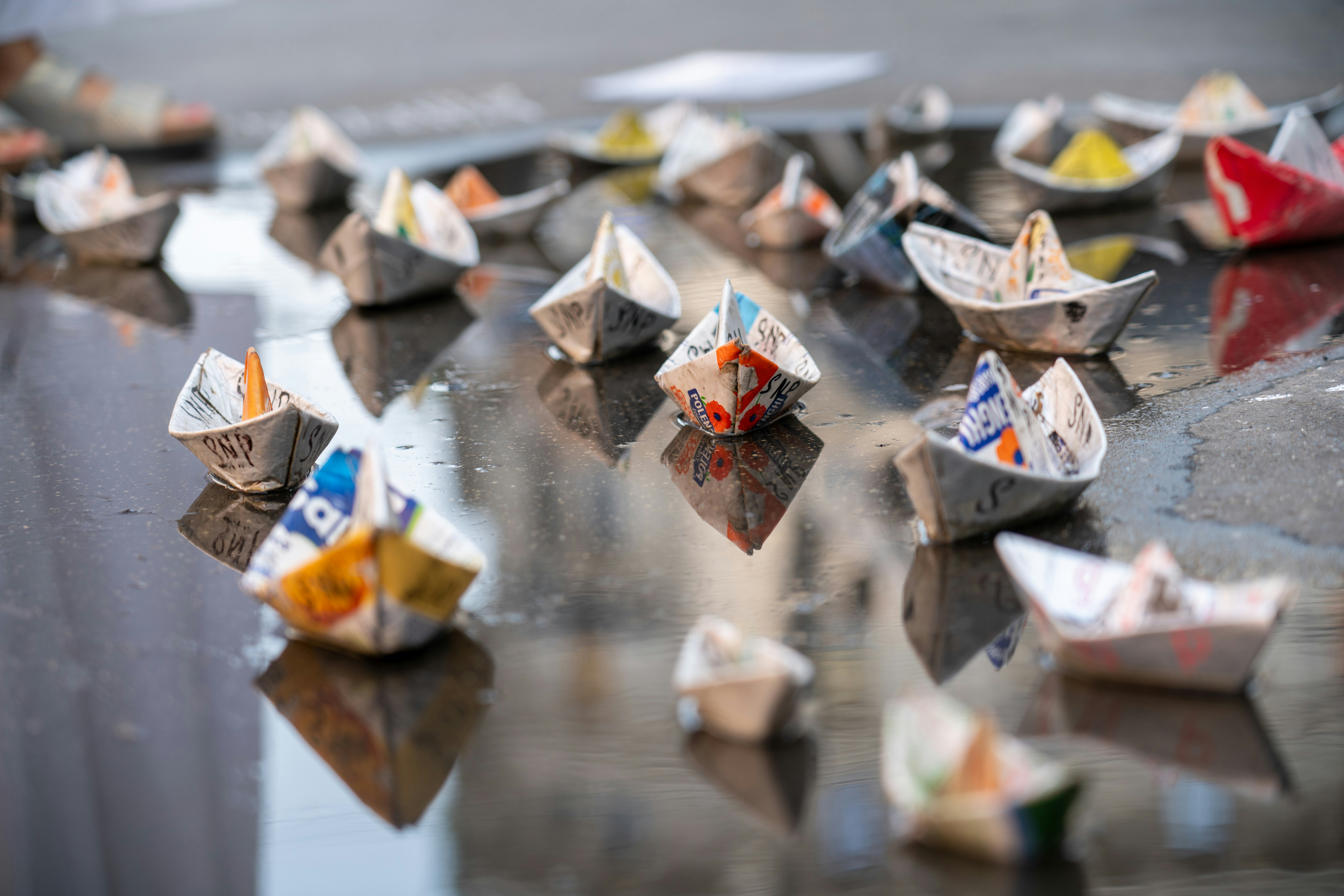Many small paper boats floating on wet ground