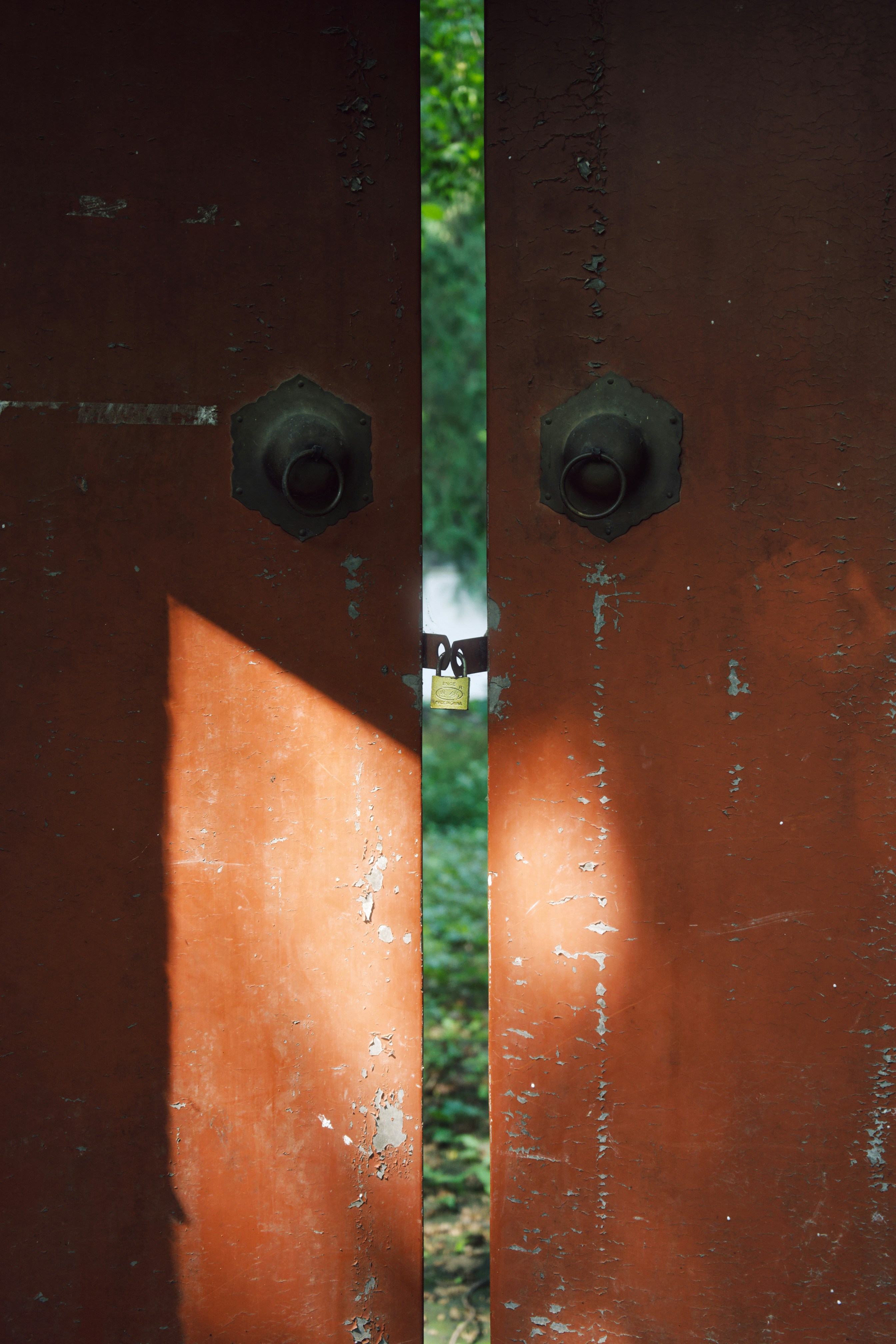 Two weathered red doors with a padlock