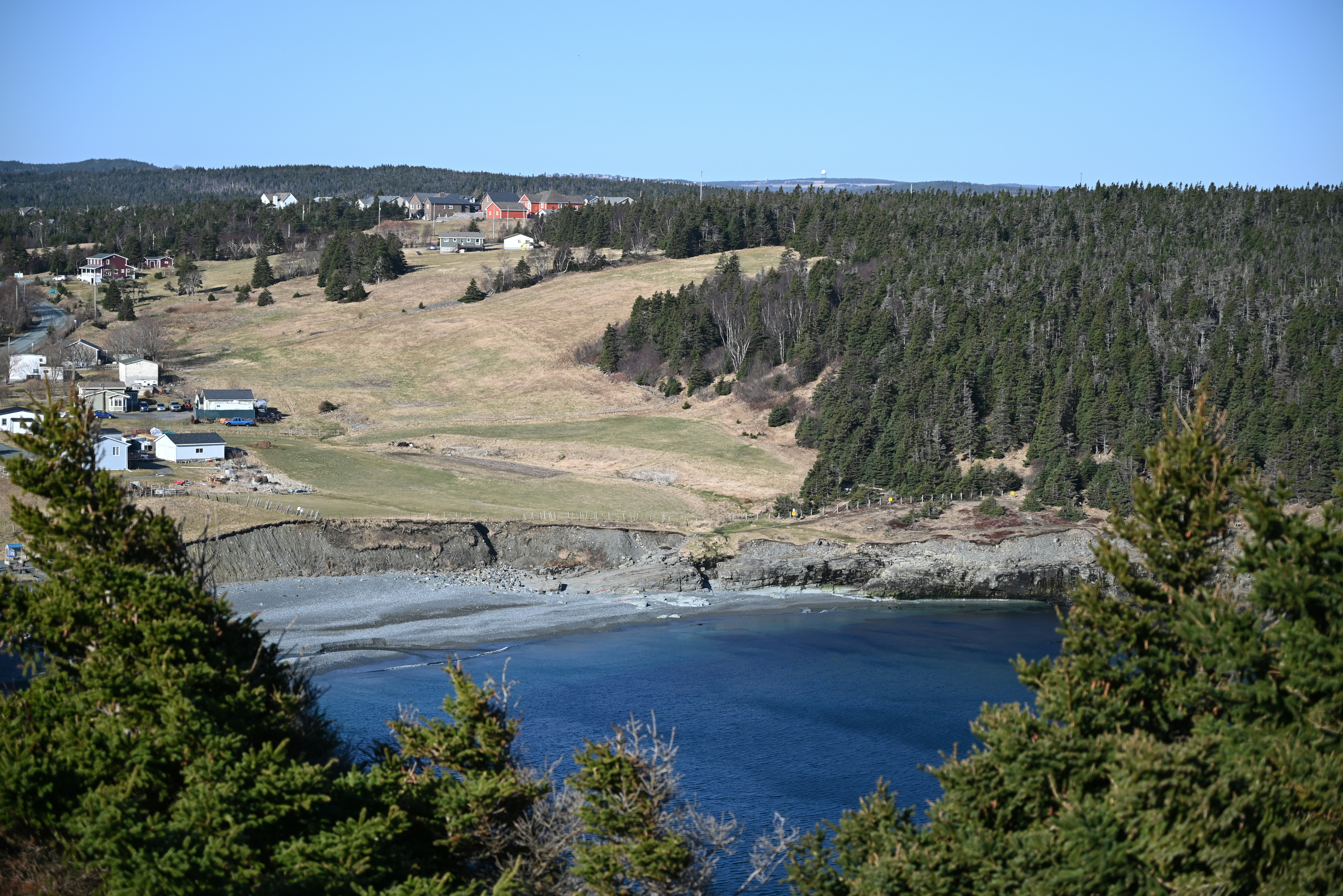なだらかな丘と木々に囲まれた海岸沿いの村