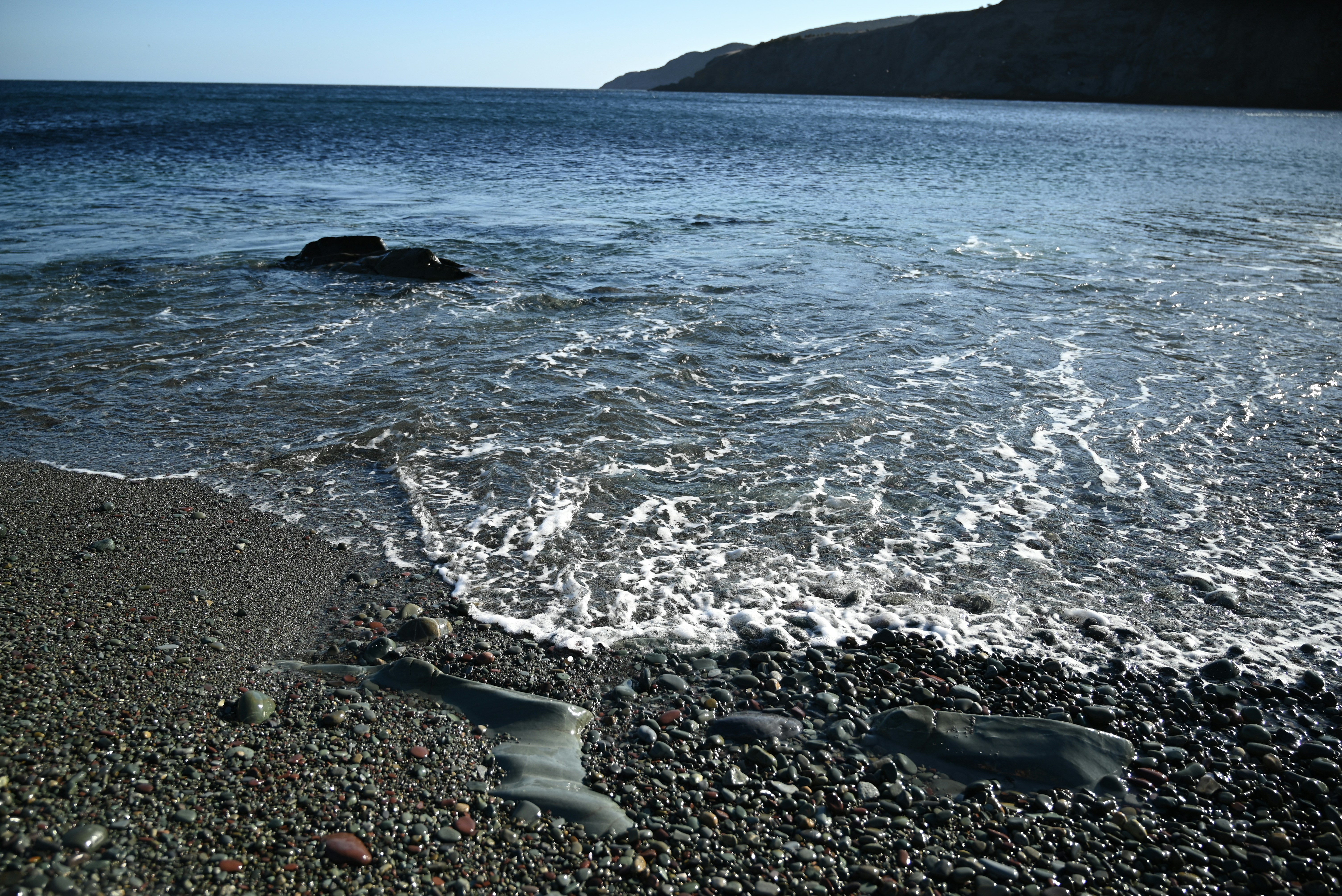 岩だらけのビーチの海岸線を穏やかな波が押し寄せる
