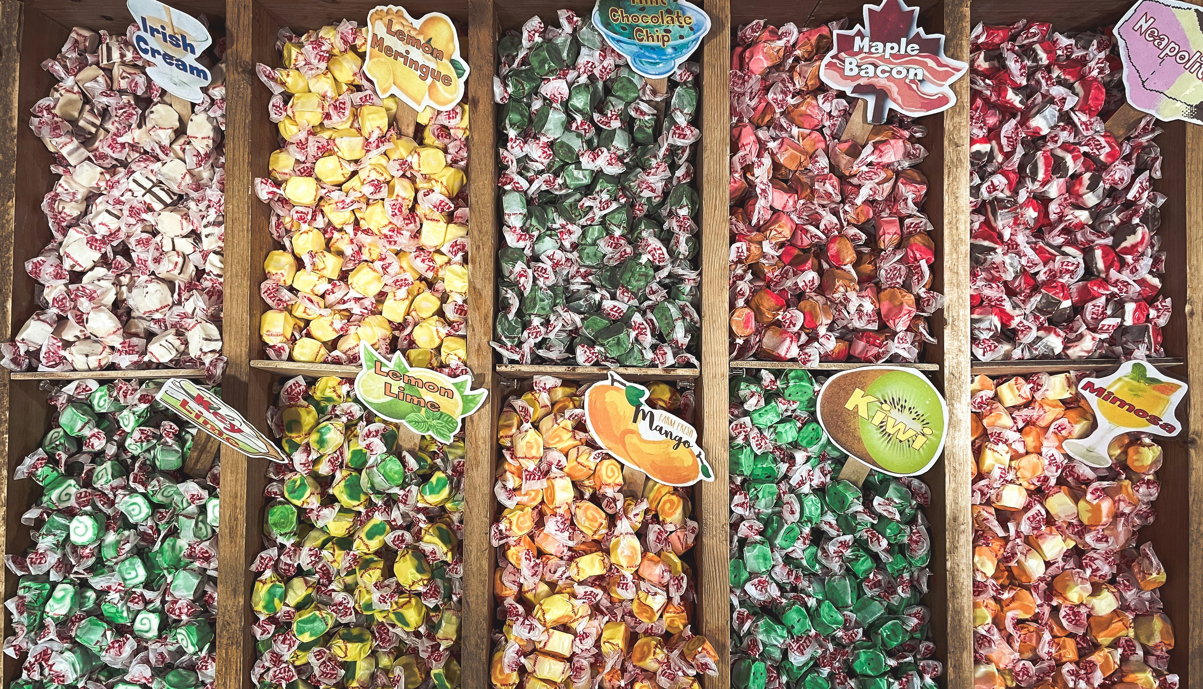 Assortment of colorful wrapped candies in wooden bins