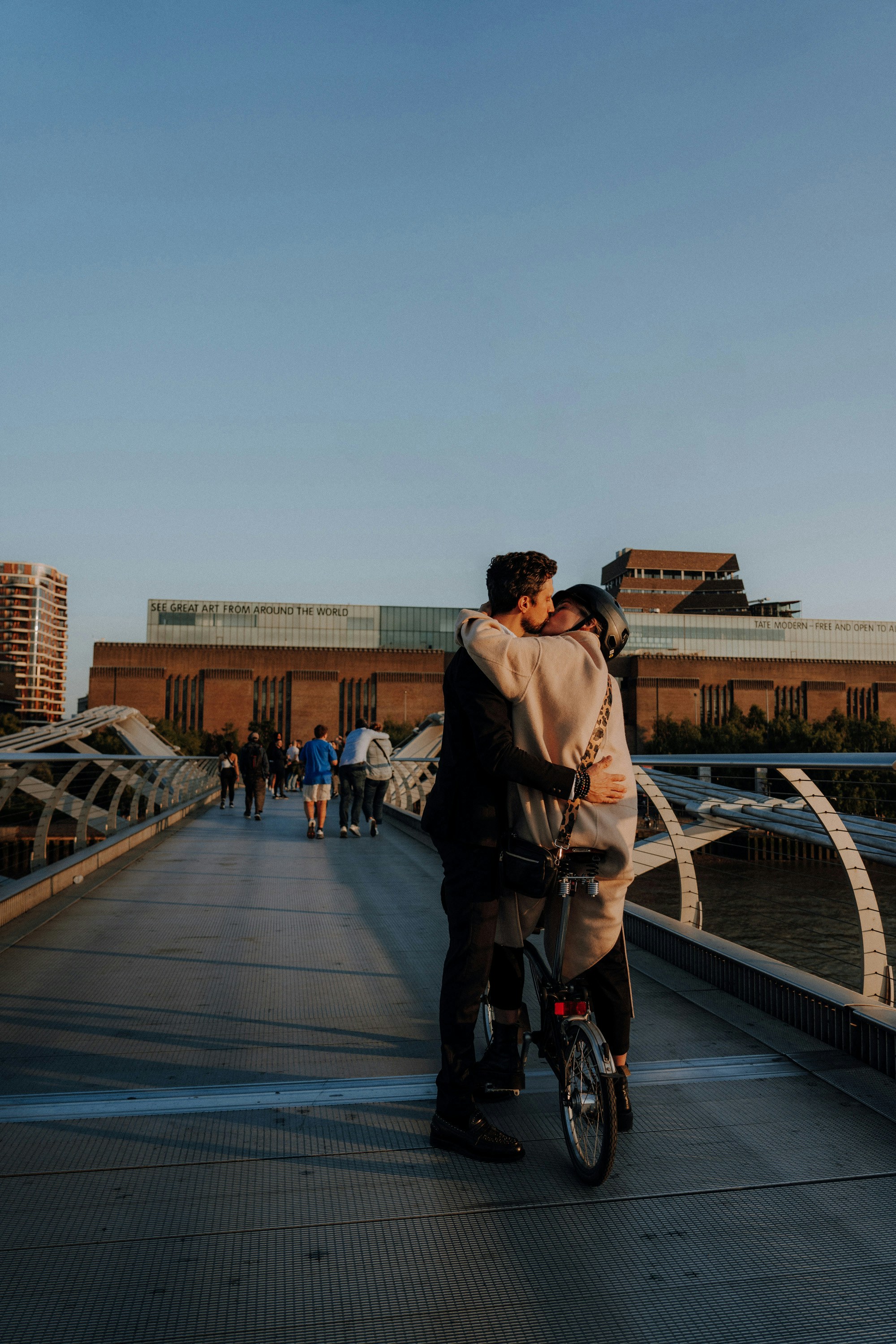 Couple kissing while riding a bicycle on a bridge