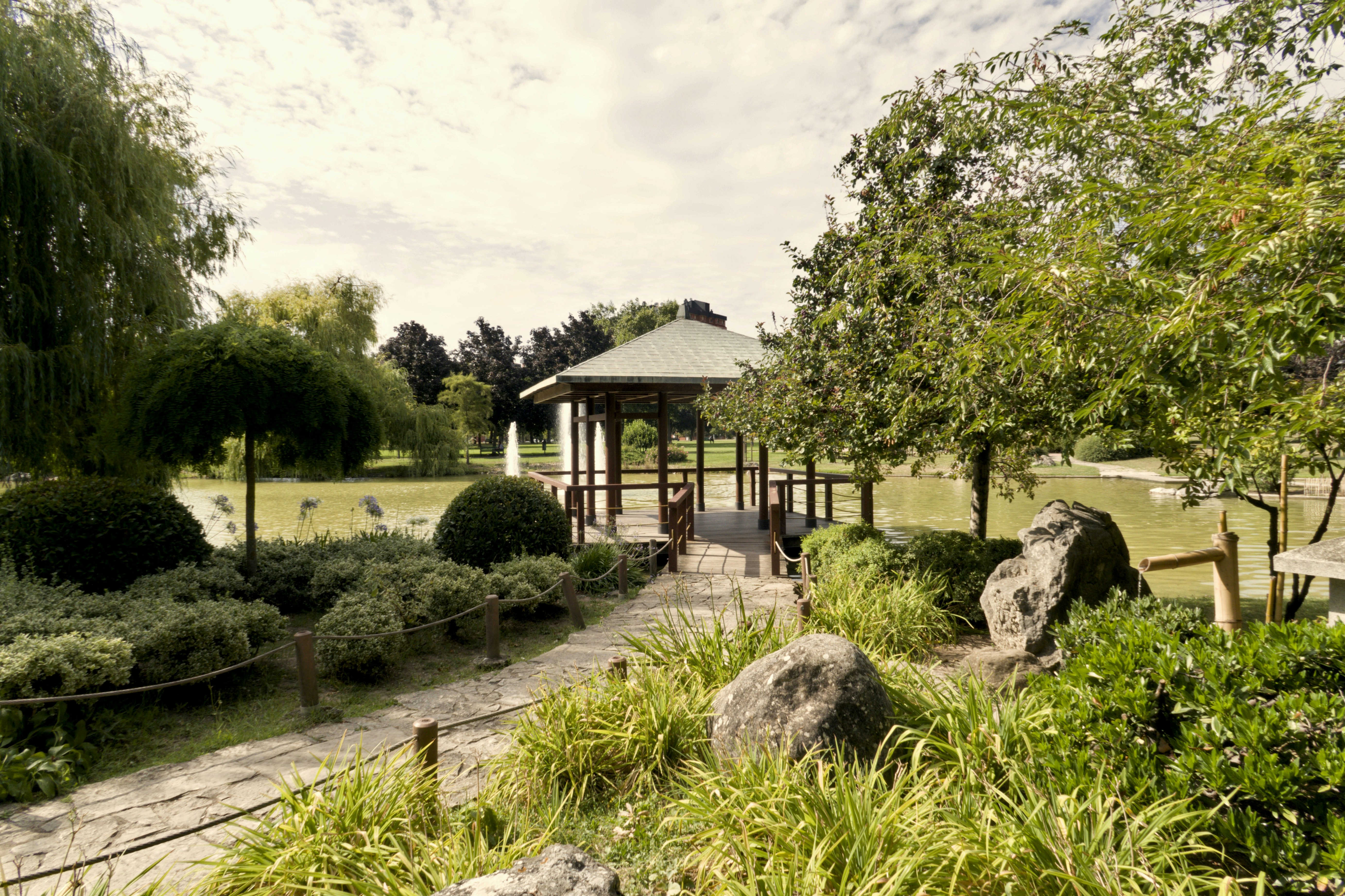 A serene japanese garden with a bridge and gazebo.