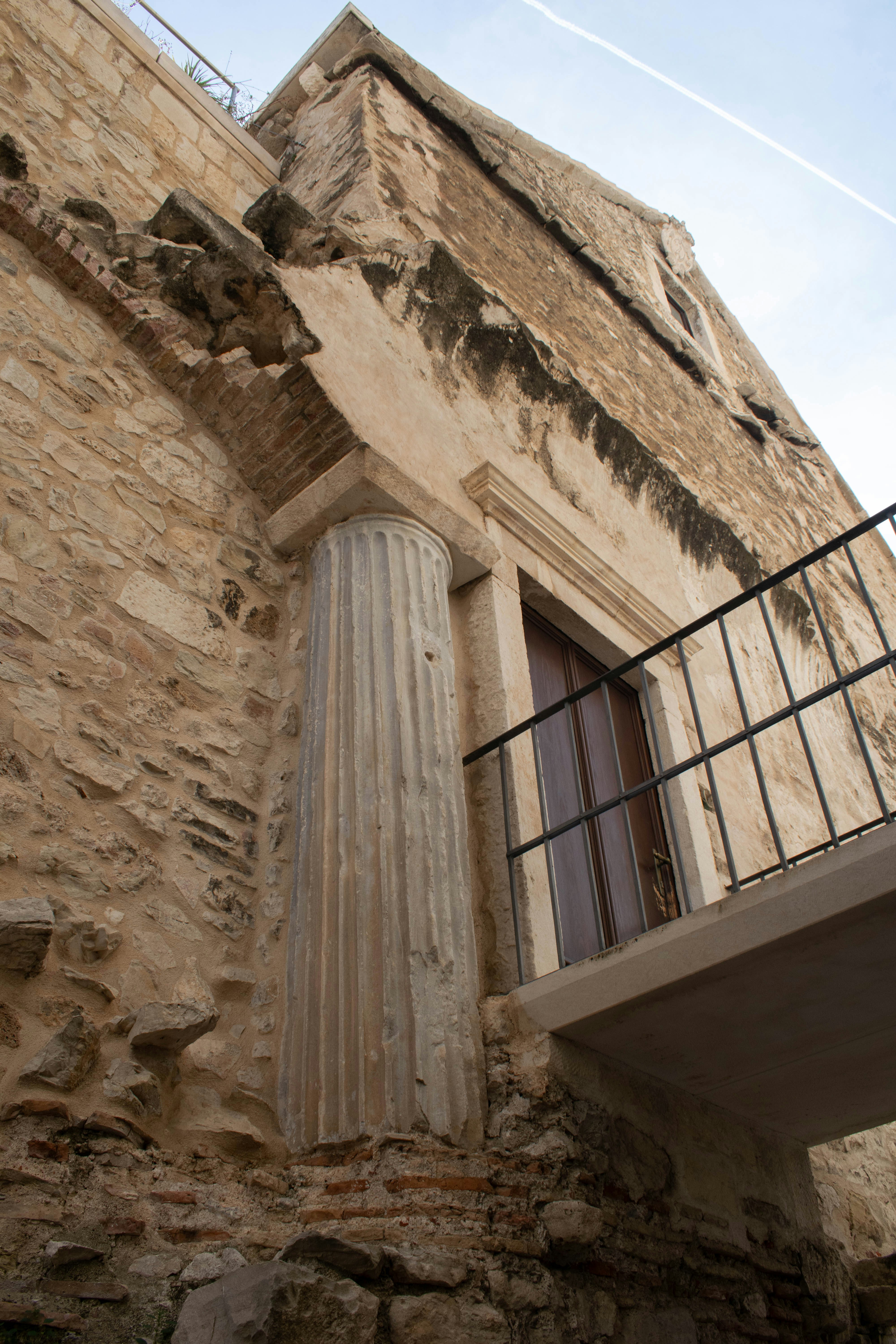 Ancient stone building with a column and balcony