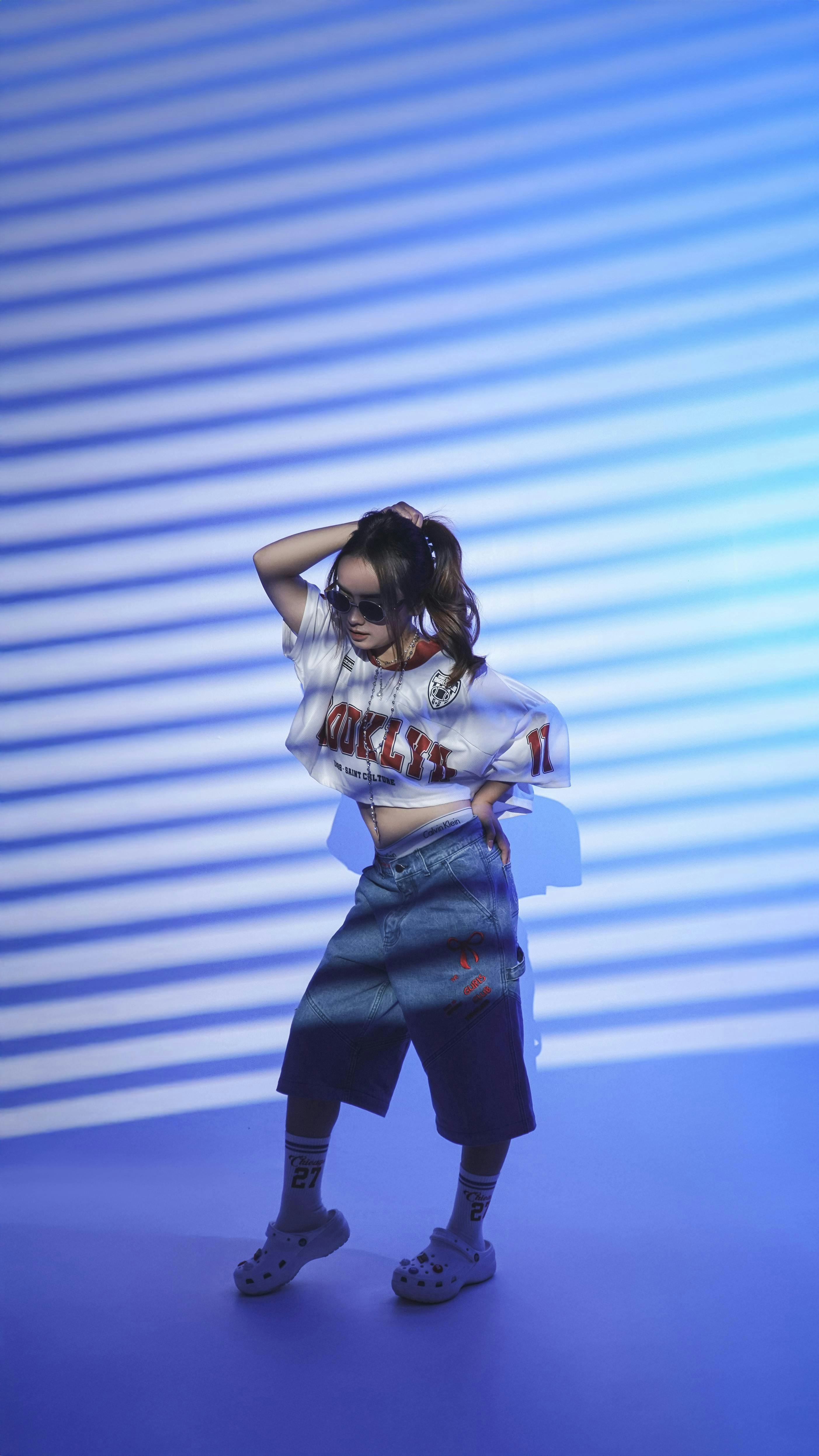 Young woman in stylish clothing posing against striped background
