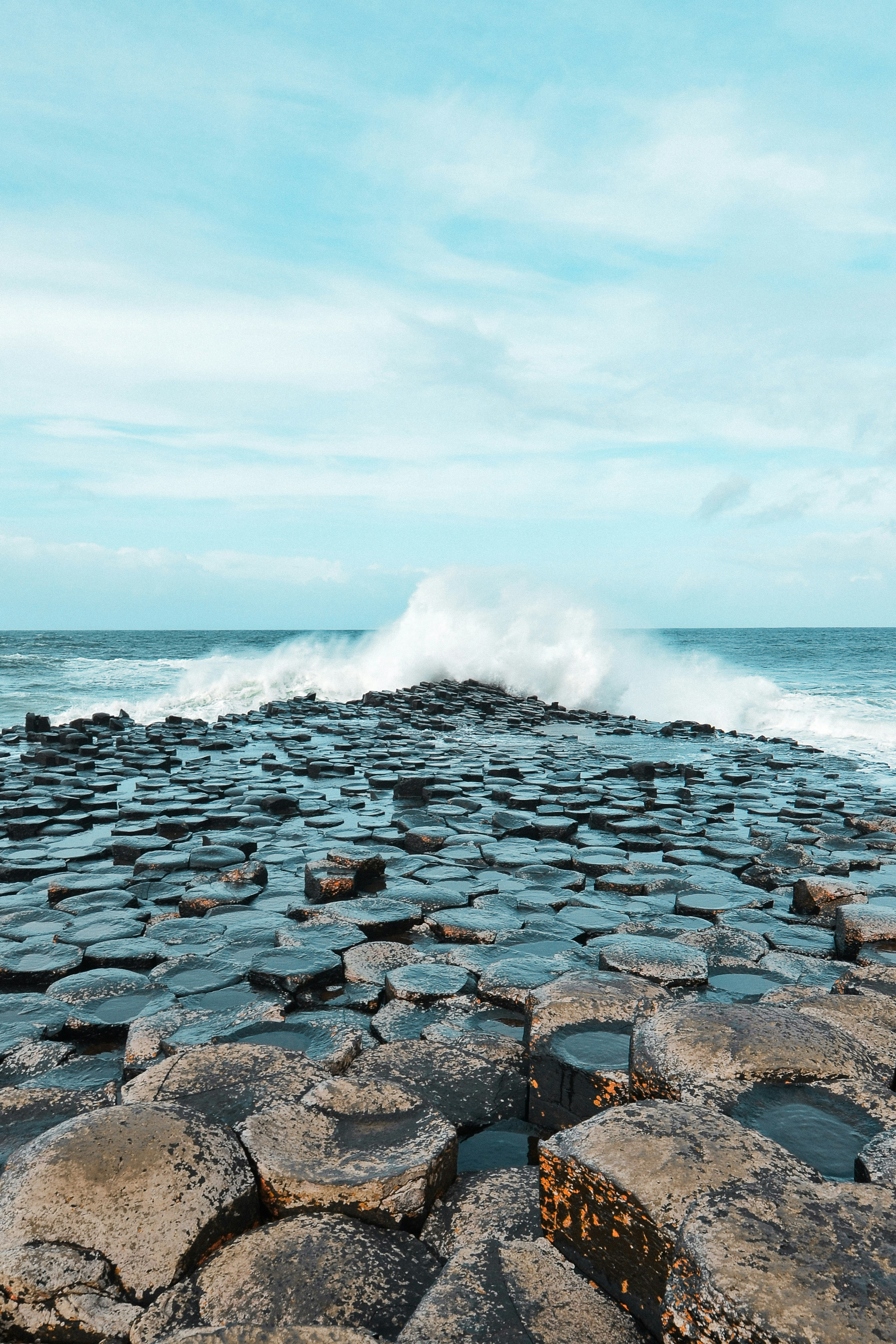 Waves crash on hexagonal rock formations by the sea