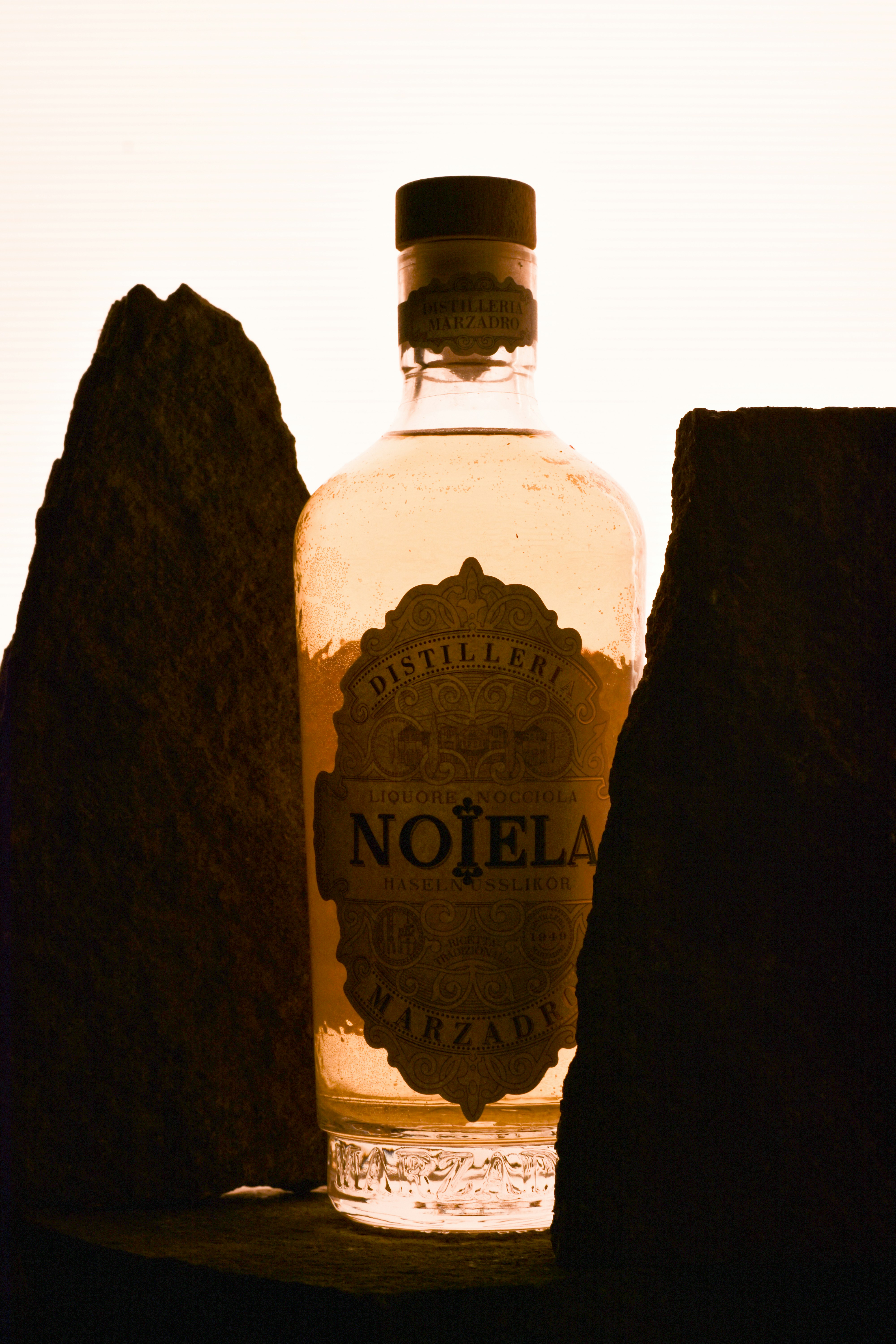 Bottle of nojela mezcal between dark rocks