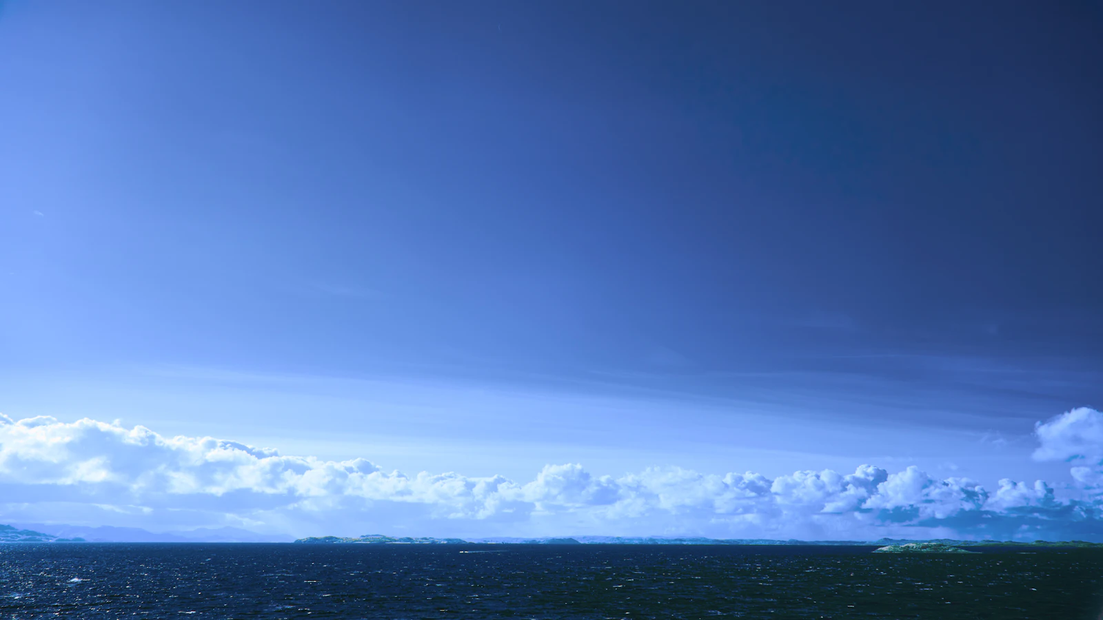 A vast, open sky meeting a calm ocean horizon