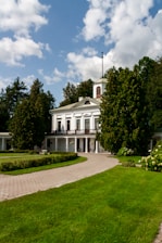 White manor house surrounded by lush green trees and gardens