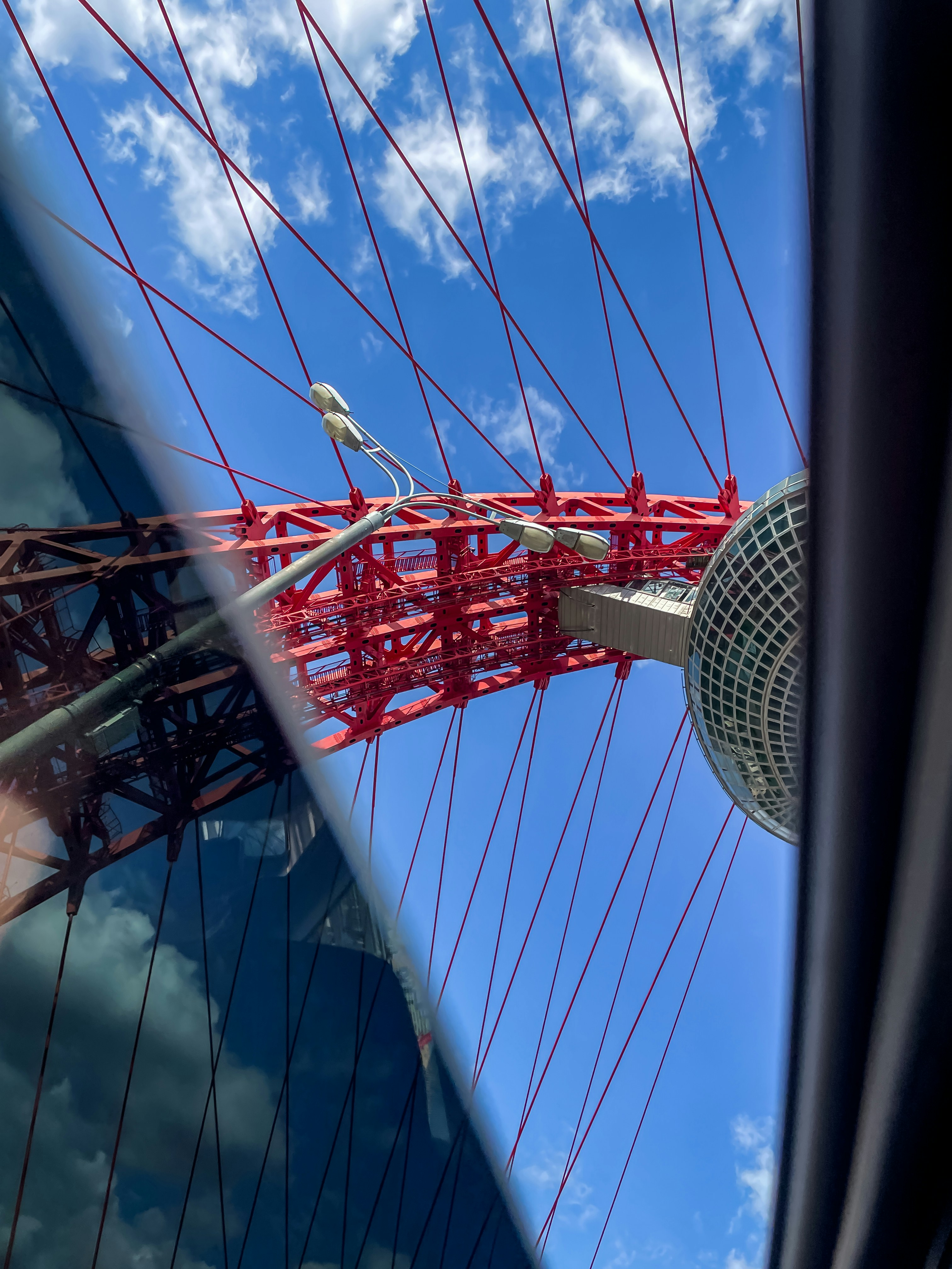Red suspension bridge structure against a blue sky