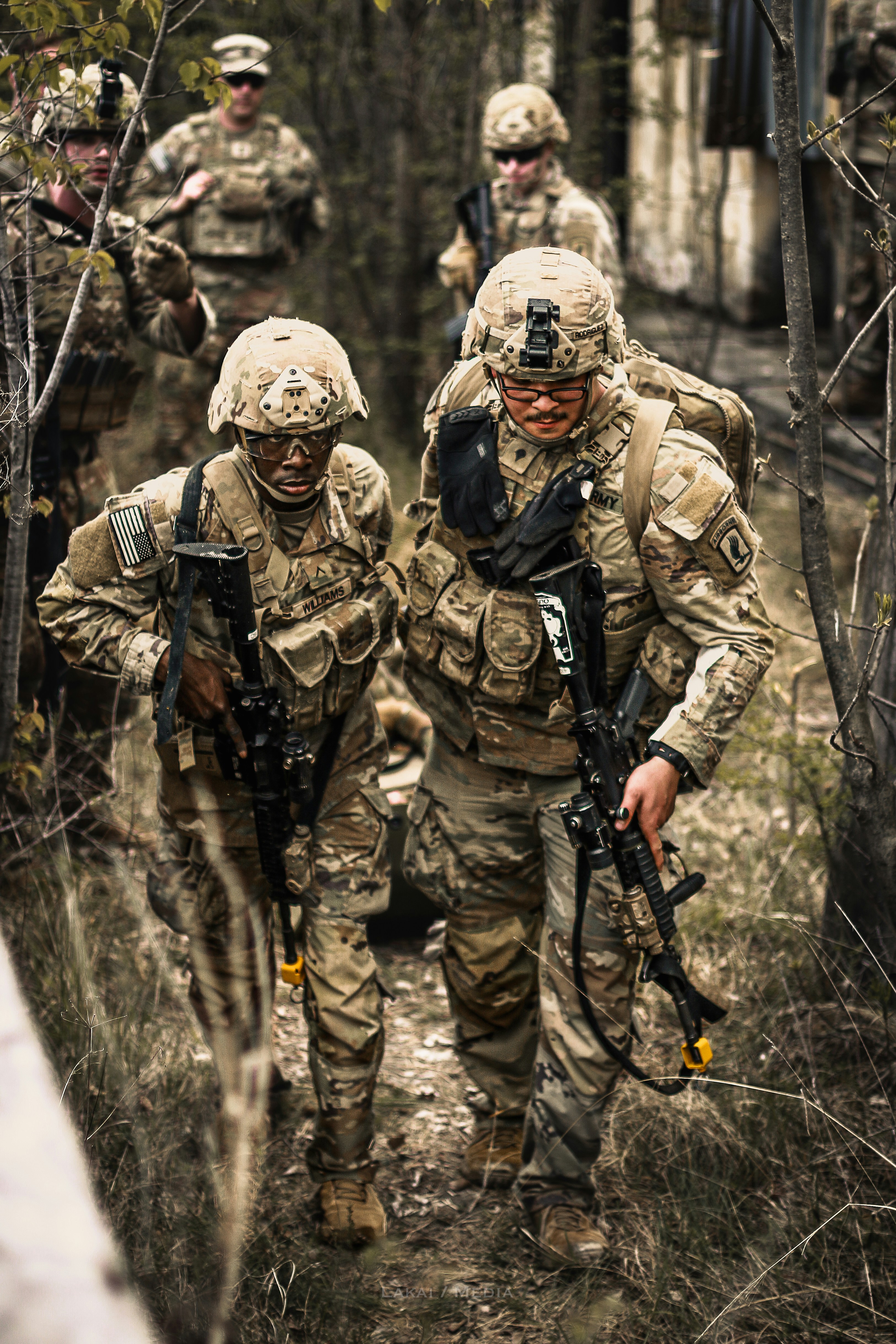Soldados con equipo de camuflaje caminando por una zona boscosa.