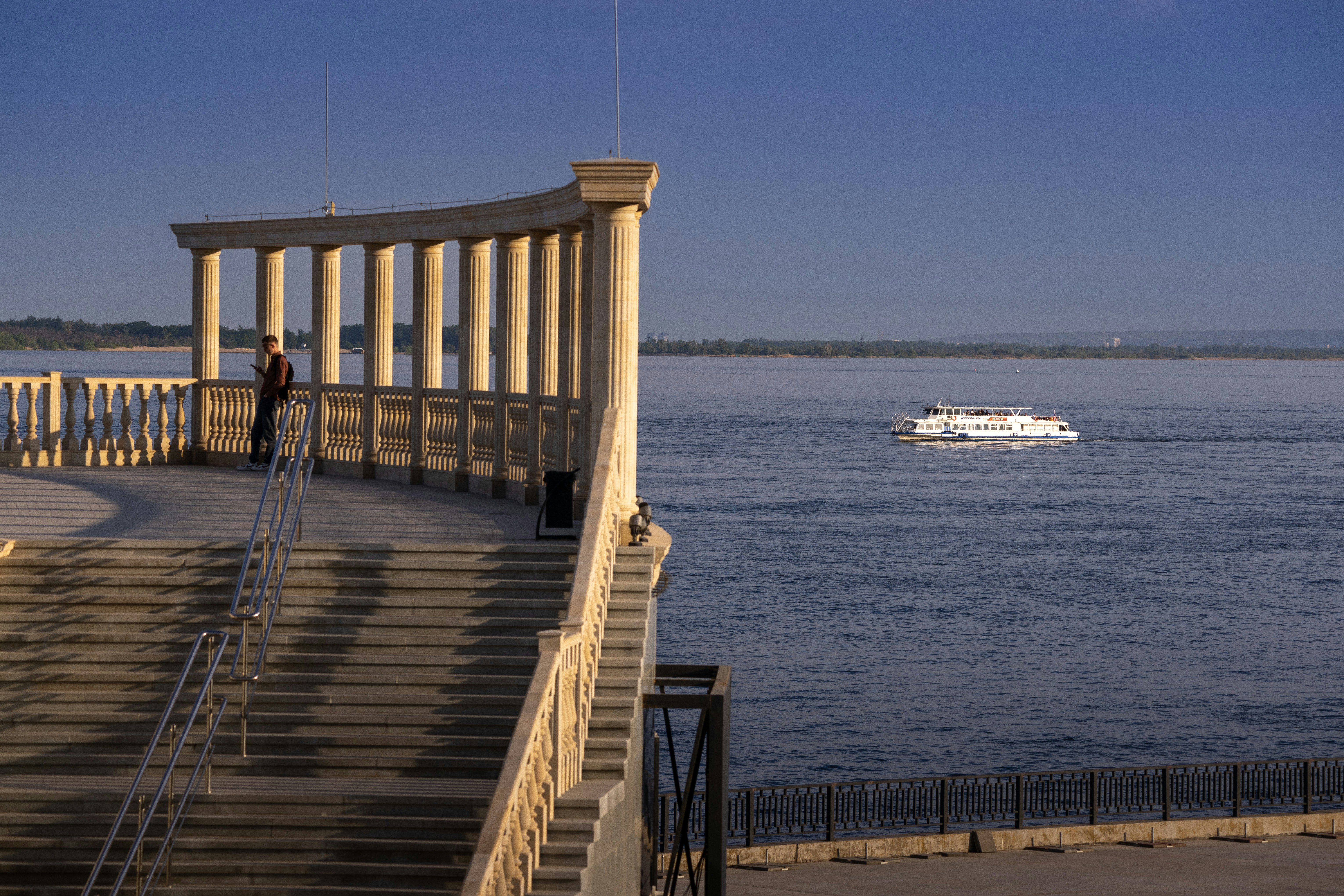 Person on promenade overlooking boat on water