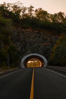 Road leading to a brightly lit tunnel entrance.