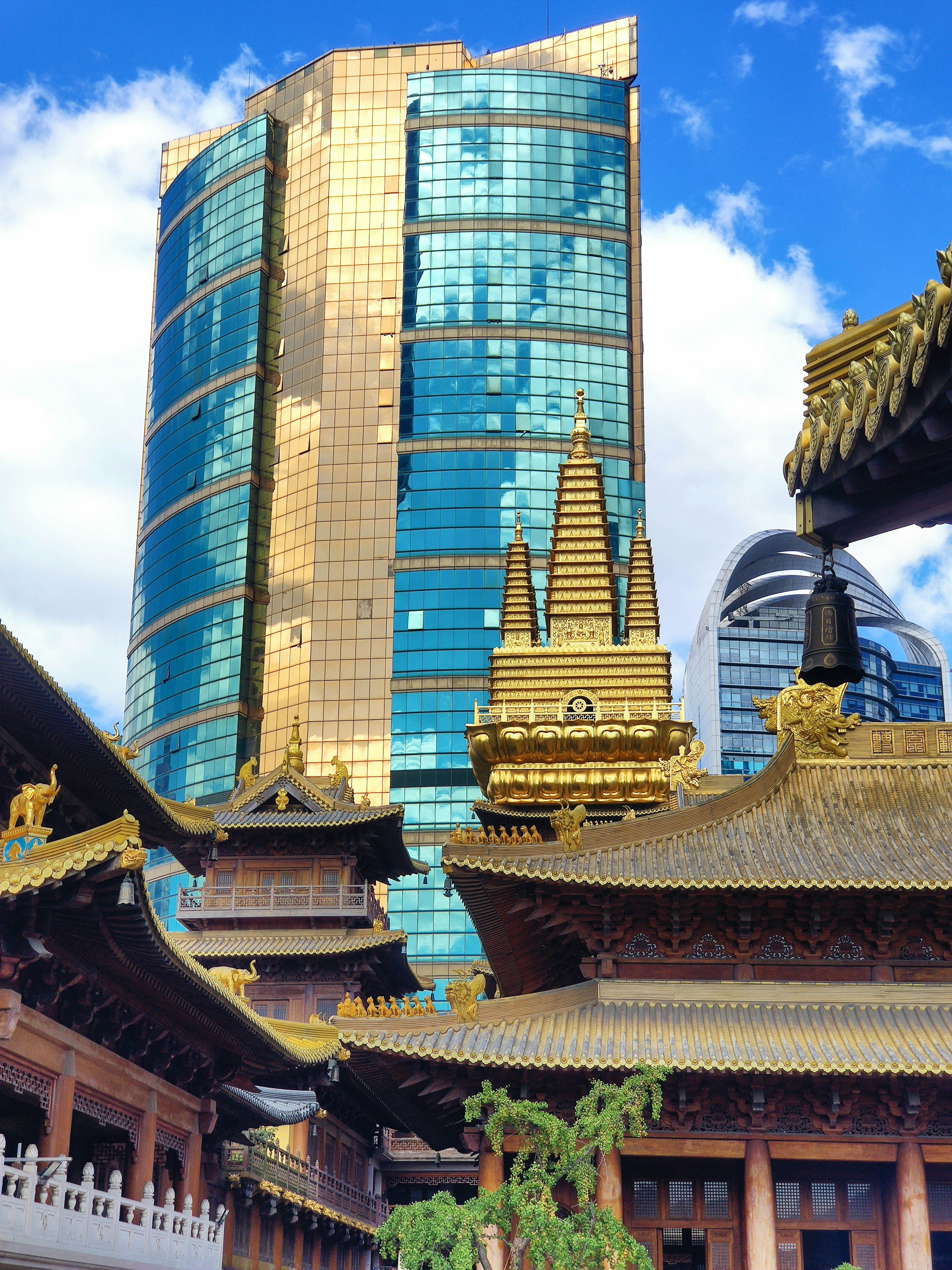 Modern skyscraper behind traditional golden temple architecture