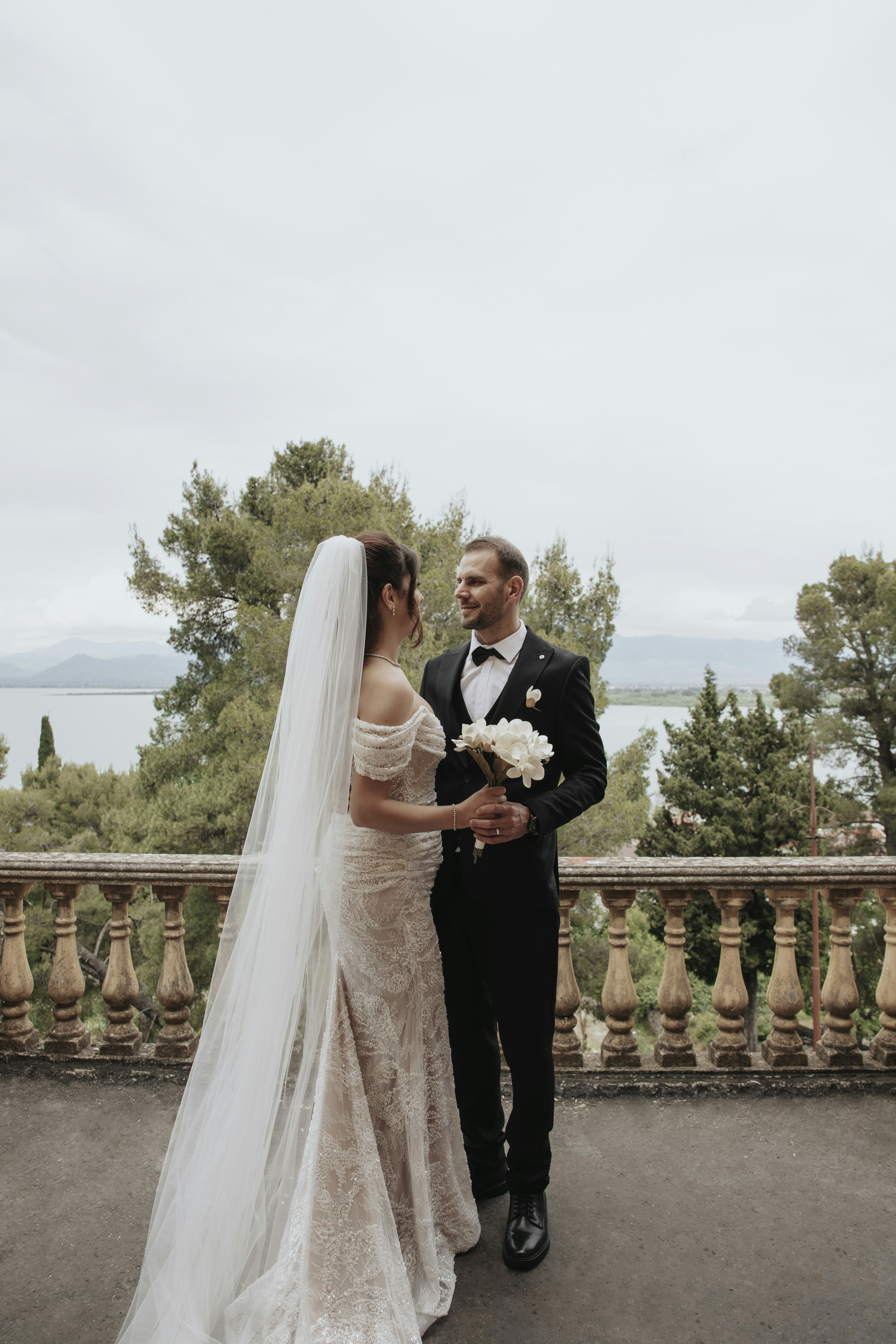 Bride and groom holding flowers on a balcony