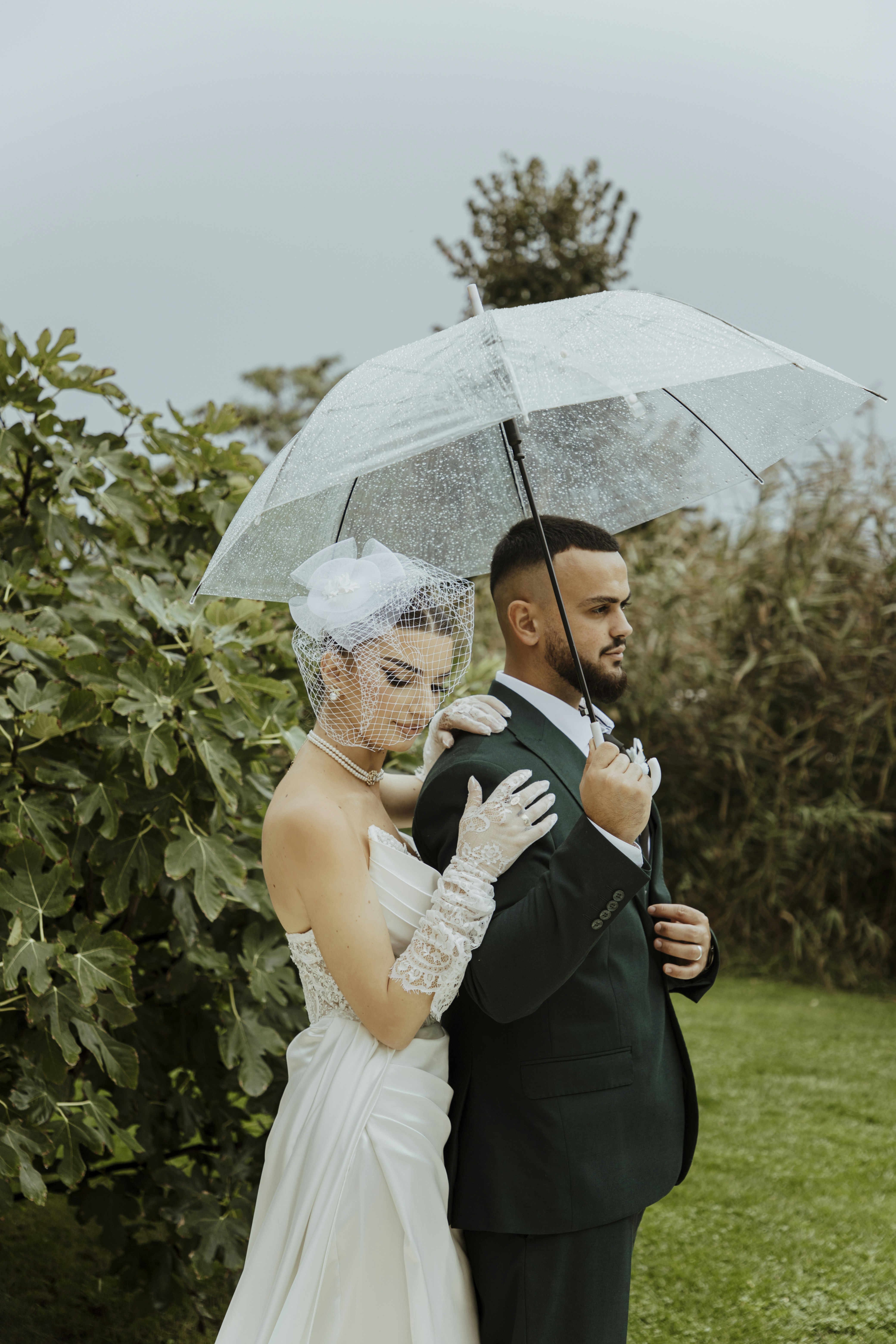 Bride and groom share an umbrella in the rain